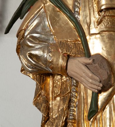 Zdjęcie nr 8: Całopostaciowa, pełnoplastyczna figura św. Szczepana stojącego w lekkim kontrapoście na niewysokiej podstawie, zwróconego w trzech czwartych w lewo. Podniesioną głowę charakteryzuje owalna twarz o młodzieńczych  rysach z niskim czołem, wysoko uniesionymi brwiami, dużymi oczami długim nosem i kształtnymi ustami w lekkim uśmiechu. Włosy krótkie, sięgające szyi, z krótką grzywką, odsłaniające uszy. Święty ubrany w srebrzoną, silnie fałdowaną albę obszytą ząbkowaną lamówką oraz złoconą, obszytą frędzlą dalmatykę z motywem korony z parą gałązek na piersiach oraz parą grubych sznurów zakończonych chwostami. Na nogach czarne buty. Lewa, zgięta w łokciu ręka wyciągnięta przed siebie z dłonią skierowaną w dół, prawą podtrzymuje kamień i gałązkę palmową.       