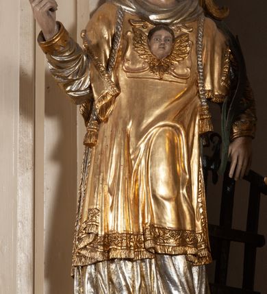 Zdjęcie nr 1: Całopostaciowa, pełnoplastyczna figura św. Wawrzyńca stojącego w kontrapoście na niewysokiej podstawie, zwróconego na wprost. Skierowaną nieznacznie w lewo głowę charakteryzuje owalna twarz o młodzieńczych  rysach z niskim czołem, wysoko uniesionymi brwiami, dużymi oczami, długim nosem i wąskimi ustami ujętymi bruzdami. Włosy krótkie, zaczesane do tyłu, odsłaniające uszy. Święty ubrany jest w srebrzoną, silnie fałdowaną albę i złoconą, obszytą glonem i frędzlą dalmatykę z motywem uskrzydlonej główki anielskiej na piersiach. Na nogach ma czarne buty. Prawa, zgięta w łokciu ręka uniesiona do góry z wyprostowanym palcem wskazującym, lewa opuszczona w dół, z gałązką palmową w dłoni.      

