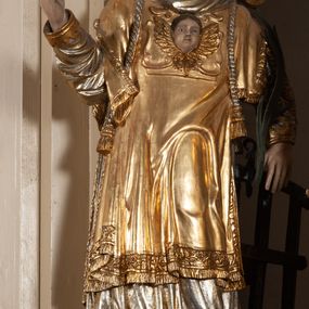 Zdjęcie nr 1: Całopostaciowa, pełnoplastyczna figura św. Wawrzyńca stojącego w kontrapoście na niewysokiej podstawie, zwróconego na wprost. Skierowaną nieznacznie w lewo głowę charakteryzuje owalna twarz o młodzieńczych  rysach z niskim czołem, wysoko uniesionymi brwiami, dużymi oczami, długim nosem i wąskimi ustami ujętymi bruzdami. Włosy krótkie, zaczesane do tyłu, odsłaniające uszy. Święty ubrany jest w srebrzoną, silnie fałdowaną albę i złoconą, obszytą glonem i frędzlą dalmatykę z motywem uskrzydlonej główki anielskiej na piersiach. Na nogach ma czarne buty. Prawa, zgięta w łokciu ręka uniesiona do góry z wyprostowanym palcem wskazującym, lewa opuszczona w dół, z gałązką palmową w dłoni.      

