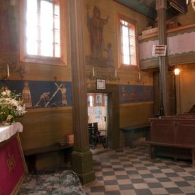 Zdjęcie nr 1: Ściany kościoła dekorują przedstawienia świętych: św. Stanisław w stroju pontyfikalnym z pastorałem, wskrzeszający Piotrowina. Poniżej na banderoli napis „BŁOGOSŁAWIENI KTÓRZY ŁAKNĄ / I PRAGNĄ SPRAWIEDLIWOŚCI”; św. Jadwiga w koronie i płaszczu podszytym gronostajem, trzymająca skrzyneczkę z klejnotami oraz krzyż z herbami Polski i Litwy. Na banderoli napis „BŁOGOSŁAWIENI / POKÓJ CZYNIĄCY”; św. Jan Kanty błogosławiący dziewczynę z dzbanem podpisany „BŁOGOSŁAWIENI / MIŁOSIERNI”; św. w habicie, z krzyżem w ręce i w asyście dwóch aniołów - jednego z palmą męczeństwa, drugiego z płonącą pochodnią, pod nimi napis „BŁOGOSŁAWIENI KTÓRZY / CIERPIĄ PRZEŚLADOWANIA DLA SPRAWIEDLIWOŚCI”; Chrystus z sercem gorejącym. Po jego prawej stronie klęczący mężczyzna, po lewej dwie owieczki nad strumieniem. Scena podpisana: „KTÓRZY PRACUJECIE I / OBCIĄŻENI JESTEŚCIE / A JA WAS OCHŁODZĘ”; archanioł Gabriel z lilią powyżej napisu  „ZDROWAŚ MARIO”; archanioł Michał z trybularzem, ponad napisem „KTÓŻ JAK BÓG!”; św. Franciszek na tle przyrody. Jest ubrany w habit franciszkański, na głowie ma kaptur. Przy prawej nodze świętego wilk, w jeziorze ryby, na niebie ptaki. Na banderoli napis „BŁOGOSŁAWIENI UBODZY DUCHEM / ALBOWIEM TAKOWYCH JEST / KRÓLESTWO NIEBIESKIE”; św. Izydor Oracz ukazany w towarzystwie anioła orającego na polu na tle dzwonnicy. Poniżej napis „BŁOGOSŁAWIENI CISI / ALBOWIEM ONI / POSIĄDĄ ZIEMIĘ”. Poniżej postaci świętych fryz z przedstawieniem 14 stacji drogi krzyżowej na błękitnym tle. Na stropie nawy i prezbiterium, na błękitnym tle, wśród kwiatowego ornamentu na środku ukazany Chrystus Ukrzyżowany ponad kielichem, gołębica Ducha Świętego i koronowana Maria. Po ich obu stronach stoją święci mężowie i niewiasty z atrybutami. W nawie w kolejności do środka: św. Wojciech (?), św. Jacek z figurą Matki Boskiej i monstrancją, klęczący św. Kazimierz w stroju książęcym z lilią, św. Agnieszka z barankiem i św. Karolina Kózkówna z różańcem, klęcząca św. Rozalia z różami, św. Klara z cyborium, św. Weronika z chustą z wizerunkiem Chrystusa, klęcząca św. Cecylia z lirą, św. Józef z lilią, św. Paweł z mieczem, klęczący św. Jan Chrzciciel z krzyżem. W prezbiterium przedstawiono 12 apostołów, niektórzy z atrybutmi, które ich jednoznacznie identyfilują, np. św. Andrzej z krzyżem w kształcie litery X, inni z księgami lub zwojami.  