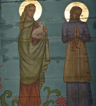 Zdjęcie nr 17: Ściany kościoła dekorują przedstawienia świętych: św. Stanisław w stroju pontyfikalnym z pastorałem, wskrzeszający Piotrowina. Poniżej na banderoli napis „BŁOGOSŁAWIENI KTÓRZY ŁAKNĄ / I PRAGNĄ SPRAWIEDLIWOŚCI”; św. Jadwiga w koronie i płaszczu podszytym gronostajem, trzymająca skrzyneczkę z klejnotami oraz krzyż z herbami Polski i Litwy. Na banderoli napis „BŁOGOSŁAWIENI / POKÓJ CZYNIĄCY”; św. Jan Kanty błogosławiący dziewczynę z dzbanem podpisany „BŁOGOSŁAWIENI / MIŁOSIERNI”; św. w habicie, z krzyżem w ręce i w asyście dwóch aniołów - jednego z palmą męczeństwa, drugiego z płonącą pochodnią, pod nimi napis „BŁOGOSŁAWIENI KTÓRZY / CIERPIĄ PRZEŚLADOWANIA DLA SPRAWIEDLIWOŚCI”; Chrystus z sercem gorejącym. Po jego prawej stronie klęczący mężczyzna, po lewej dwie owieczki nad strumieniem. Scena podpisana: „KTÓRZY PRACUJECIE I / OBCIĄŻENI JESTEŚCIE / A JA WAS OCHŁODZĘ”; archanioł Gabriel z lilią powyżej napisu  „ZDROWAŚ MARIO”; archanioł Michał z trybularzem, ponad napisem „KTÓŻ JAK BÓG!”; św. Franciszek na tle przyrody. Jest ubrany w habit franciszkański, na głowie ma kaptur. Przy prawej nodze świętego wilk, w jeziorze ryby, na niebie ptaki. Na banderoli napis „BŁOGOSŁAWIENI UBODZY DUCHEM / ALBOWIEM TAKOWYCH JEST / KRÓLESTWO NIEBIESKIE”; św. Izydor Oracz ukazany w towarzystwie anioła orającego na polu na tle dzwonnicy. Poniżej napis „BŁOGOSŁAWIENI CISI / ALBOWIEM ONI / POSIĄDĄ ZIEMIĘ”. Poniżej postaci świętych fryz z przedstawieniem 14 stacji drogi krzyżowej na błękitnym tle. Na stropie nawy i prezbiterium, na błękitnym tle, wśród kwiatowego ornamentu na środku ukazany Chrystus Ukrzyżowany ponad kielichem, gołębica Ducha Świętego i koronowana Maria. Po ich obu stronach stoją święci mężowie i niewiasty z atrybutami. W nawie w kolejności do środka: św. Wojciech (?), św. Jacek z figurą Matki Boskiej i monstrancją, klęczący św. Kazimierz w stroju książęcym z lilią, św. Agnieszka z barankiem i św. Karolina Kózkówna z różańcem, klęcząca św. Rozalia z różami, św. Klara z cyborium, św. Weronika z chustą z wizerunkiem Chrystusa, klęcząca św. Cecylia z lirą, św. Józef z lilią, św. Paweł z mieczem, klęczący św. Jan Chrzciciel z krzyżem. W prezbiterium przedstawiono 12 apostołów, niektórzy z atrybutmi, które ich jednoznacznie identyfilują, np. św. Andrzej z krzyżem w kształcie litery X, inni z księgami lub zwojami.  