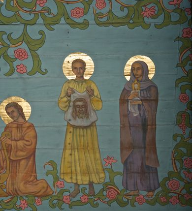 Zdjęcie nr 16: Ściany kościoła dekorują przedstawienia świętych: św. Stanisław w stroju pontyfikalnym z pastorałem, wskrzeszający Piotrowina. Poniżej na banderoli napis „BŁOGOSŁAWIENI KTÓRZY ŁAKNĄ / I PRAGNĄ SPRAWIEDLIWOŚCI”; św. Jadwiga w koronie i płaszczu podszytym gronostajem, trzymająca skrzyneczkę z klejnotami oraz krzyż z herbami Polski i Litwy. Na banderoli napis „BŁOGOSŁAWIENI / POKÓJ CZYNIĄCY”; św. Jan Kanty błogosławiący dziewczynę z dzbanem podpisany „BŁOGOSŁAWIENI / MIŁOSIERNI”; św. w habicie, z krzyżem w ręce i w asyście dwóch aniołów - jednego z palmą męczeństwa, drugiego z płonącą pochodnią, pod nimi napis „BŁOGOSŁAWIENI KTÓRZY / CIERPIĄ PRZEŚLADOWANIA DLA SPRAWIEDLIWOŚCI”; Chrystus z sercem gorejącym. Po jego prawej stronie klęczący mężczyzna, po lewej dwie owieczki nad strumieniem. Scena podpisana: „KTÓRZY PRACUJECIE I / OBCIĄŻENI JESTEŚCIE / A JA WAS OCHŁODZĘ”; archanioł Gabriel z lilią powyżej napisu  „ZDROWAŚ MARIO”; archanioł Michał z trybularzem, ponad napisem „KTÓŻ JAK BÓG!”; św. Franciszek na tle przyrody. Jest ubrany w habit franciszkański, na głowie ma kaptur. Przy prawej nodze świętego wilk, w jeziorze ryby, na niebie ptaki. Na banderoli napis „BŁOGOSŁAWIENI UBODZY DUCHEM / ALBOWIEM TAKOWYCH JEST / KRÓLESTWO NIEBIESKIE”; św. Izydor Oracz ukazany w towarzystwie anioła orającego na polu na tle dzwonnicy. Poniżej napis „BŁOGOSŁAWIENI CISI / ALBOWIEM ONI / POSIĄDĄ ZIEMIĘ”. Poniżej postaci świętych fryz z przedstawieniem 14 stacji drogi krzyżowej na błękitnym tle. Na stropie nawy i prezbiterium, na błękitnym tle, wśród kwiatowego ornamentu na środku ukazany Chrystus Ukrzyżowany ponad kielichem, gołębica Ducha Świętego i koronowana Maria. Po ich obu stronach stoją święci mężowie i niewiasty z atrybutami. W nawie w kolejności do środka: św. Wojciech (?), św. Jacek z figurą Matki Boskiej i monstrancją, klęczący św. Kazimierz w stroju książęcym z lilią, św. Agnieszka z barankiem i św. Karolina Kózkówna z różańcem, klęcząca św. Rozalia z różami, św. Klara z cyborium, św. Weronika z chustą z wizerunkiem Chrystusa, klęcząca św. Cecylia z lirą, św. Józef z lilią, św. Paweł z mieczem, klęczący św. Jan Chrzciciel z krzyżem. W prezbiterium przedstawiono 12 apostołów, niektórzy z atrybutmi, które ich jednoznacznie identyfilują, np. św. Andrzej z krzyżem w kształcie litery X, inni z księgami lub zwojami.  