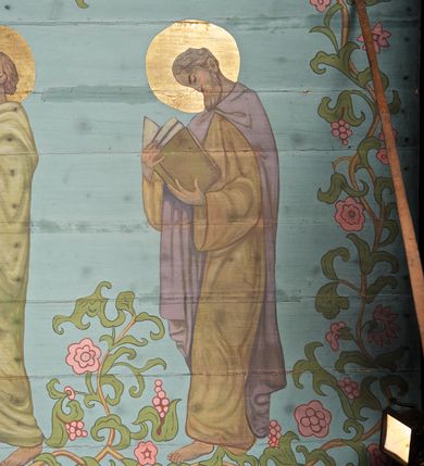 Zdjęcie nr 24: Ściany kościoła dekorują przedstawienia świętych: św. Stanisław w stroju pontyfikalnym z pastorałem, wskrzeszający Piotrowina. Poniżej na banderoli napis „BŁOGOSŁAWIENI KTÓRZY ŁAKNĄ / I PRAGNĄ SPRAWIEDLIWOŚCI”; św. Jadwiga w koronie i płaszczu podszytym gronostajem, trzymająca skrzyneczkę z klejnotami oraz krzyż z herbami Polski i Litwy. Na banderoli napis „BŁOGOSŁAWIENI / POKÓJ CZYNIĄCY”; św. Jan Kanty błogosławiący dziewczynę z dzbanem podpisany „BŁOGOSŁAWIENI / MIŁOSIERNI”; św. w habicie, z krzyżem w ręce i w asyście dwóch aniołów - jednego z palmą męczeństwa, drugiego z płonącą pochodnią, pod nimi napis „BŁOGOSŁAWIENI KTÓRZY / CIERPIĄ PRZEŚLADOWANIA DLA SPRAWIEDLIWOŚCI”; Chrystus z sercem gorejącym. Po jego prawej stronie klęczący mężczyzna, po lewej dwie owieczki nad strumieniem. Scena podpisana: „KTÓRZY PRACUJECIE I / OBCIĄŻENI JESTEŚCIE / A JA WAS OCHŁODZĘ”; archanioł Gabriel z lilią powyżej napisu  „ZDROWAŚ MARIO”; archanioł Michał z trybularzem, ponad napisem „KTÓŻ JAK BÓG!”; św. Franciszek na tle przyrody. Jest ubrany w habit franciszkański, na głowie ma kaptur. Przy prawej nodze świętego wilk, w jeziorze ryby, na niebie ptaki. Na banderoli napis „BŁOGOSŁAWIENI UBODZY DUCHEM / ALBOWIEM TAKOWYCH JEST / KRÓLESTWO NIEBIESKIE”; św. Izydor Oracz ukazany w towarzystwie anioła orającego na polu na tle dzwonnicy. Poniżej napis „BŁOGOSŁAWIENI CISI / ALBOWIEM ONI / POSIĄDĄ ZIEMIĘ”. Poniżej postaci świętych fryz z przedstawieniem 14 stacji drogi krzyżowej na błękitnym tle. Na stropie nawy i prezbiterium, na błękitnym tle, wśród kwiatowego ornamentu na środku ukazany Chrystus Ukrzyżowany ponad kielichem, gołębica Ducha Świętego i koronowana Maria. Po ich obu stronach stoją święci mężowie i niewiasty z atrybutami. W nawie w kolejności do środka: św. Wojciech (?), św. Jacek z figurą Matki Boskiej i monstrancją, klęczący św. Kazimierz w stroju książęcym z lilią, św. Agnieszka z barankiem i św. Karolina Kózkówna z różańcem, klęcząca św. Rozalia z różami, św. Klara z cyborium, św. Weronika z chustą z wizerunkiem Chrystusa, klęcząca św. Cecylia z lirą, św. Józef z lilią, św. Paweł z mieczem, klęczący św. Jan Chrzciciel z krzyżem. W prezbiterium przedstawiono 12 apostołów, niektórzy z atrybutmi, które ich jednoznacznie identyfilują, np. św. Andrzej z krzyżem w kształcie litery X, inni z księgami lub zwojami.  