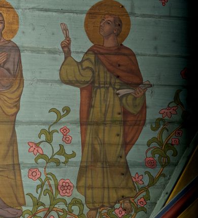 Zdjęcie nr 31: Ściany kościoła dekorują przedstawienia świętych: św. Stanisław w stroju pontyfikalnym z pastorałem, wskrzeszający Piotrowina. Poniżej na banderoli napis „BŁOGOSŁAWIENI KTÓRZY ŁAKNĄ / I PRAGNĄ SPRAWIEDLIWOŚCI”; św. Jadwiga w koronie i płaszczu podszytym gronostajem, trzymająca skrzyneczkę z klejnotami oraz krzyż z herbami Polski i Litwy. Na banderoli napis „BŁOGOSŁAWIENI / POKÓJ CZYNIĄCY”; św. Jan Kanty błogosławiący dziewczynę z dzbanem podpisany „BŁOGOSŁAWIENI / MIŁOSIERNI”; św. w habicie, z krzyżem w ręce i w asyście dwóch aniołów - jednego z palmą męczeństwa, drugiego z płonącą pochodnią, pod nimi napis „BŁOGOSŁAWIENI KTÓRZY / CIERPIĄ PRZEŚLADOWANIA DLA SPRAWIEDLIWOŚCI”; Chrystus z sercem gorejącym. Po jego prawej stronie klęczący mężczyzna, po lewej dwie owieczki nad strumieniem. Scena podpisana: „KTÓRZY PRACUJECIE I / OBCIĄŻENI JESTEŚCIE / A JA WAS OCHŁODZĘ”; archanioł Gabriel z lilią powyżej napisu  „ZDROWAŚ MARIO”; archanioł Michał z trybularzem, ponad napisem „KTÓŻ JAK BÓG!”; św. Franciszek na tle przyrody. Jest ubrany w habit franciszkański, na głowie ma kaptur. Przy prawej nodze świętego wilk, w jeziorze ryby, na niebie ptaki. Na banderoli napis „BŁOGOSŁAWIENI UBODZY DUCHEM / ALBOWIEM TAKOWYCH JEST / KRÓLESTWO NIEBIESKIE”; św. Izydor Oracz ukazany w towarzystwie anioła orającego na polu na tle dzwonnicy. Poniżej napis „BŁOGOSŁAWIENI CISI / ALBOWIEM ONI / POSIĄDĄ ZIEMIĘ”. Poniżej postaci świętych fryz z przedstawieniem 14 stacji drogi krzyżowej na błękitnym tle. Na stropie nawy i prezbiterium, na błękitnym tle, wśród kwiatowego ornamentu na środku ukazany Chrystus Ukrzyżowany ponad kielichem, gołębica Ducha Świętego i koronowana Maria. Po ich obu stronach stoją święci mężowie i niewiasty z atrybutami. W nawie w kolejności do środka: św. Wojciech (?), św. Jacek z figurą Matki Boskiej i monstrancją, klęczący św. Kazimierz w stroju książęcym z lilią, św. Agnieszka z barankiem i św. Karolina Kózkówna z różańcem, klęcząca św. Rozalia z różami, św. Klara z cyborium, św. Weronika z chustą z wizerunkiem Chrystusa, klęcząca św. Cecylia z lirą, św. Józef z lilią, św. Paweł z mieczem, klęczący św. Jan Chrzciciel z krzyżem. W prezbiterium przedstawiono 12 apostołów, niektórzy z atrybutmi, które ich jednoznacznie identyfilują, np. św. Andrzej z krzyżem w kształcie litery X, inni z księgami lub zwojami.  