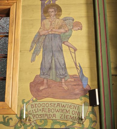 Zdjęcie nr 7: Ściany kościoła dekorują przedstawienia świętych: św. Stanisław w stroju pontyfikalnym z pastorałem, wskrzeszający Piotrowina. Poniżej na banderoli napis „BŁOGOSŁAWIENI KTÓRZY ŁAKNĄ / I PRAGNĄ SPRAWIEDLIWOŚCI”; św. Jadwiga w koronie i płaszczu podszytym gronostajem, trzymająca skrzyneczkę z klejnotami oraz krzyż z herbami Polski i Litwy. Na banderoli napis „BŁOGOSŁAWIENI / POKÓJ CZYNIĄCY”; św. Jan Kanty błogosławiący dziewczynę z dzbanem podpisany „BŁOGOSŁAWIENI / MIŁOSIERNI”; św. w habicie, z krzyżem w ręce i w asyście dwóch aniołów - jednego z palmą męczeństwa, drugiego z płonącą pochodnią, pod nimi napis „BŁOGOSŁAWIENI KTÓRZY / CIERPIĄ PRZEŚLADOWANIA DLA SPRAWIEDLIWOŚCI”; Chrystus z sercem gorejącym. Po jego prawej stronie klęczący mężczyzna, po lewej dwie owieczki nad strumieniem. Scena podpisana: „KTÓRZY PRACUJECIE I / OBCIĄŻENI JESTEŚCIE / A JA WAS OCHŁODZĘ”; archanioł Gabriel z lilią powyżej napisu  „ZDROWAŚ MARIO”; archanioł Michał z trybularzem, ponad napisem „KTÓŻ JAK BÓG!”; św. Franciszek na tle przyrody. Jest ubrany w habit franciszkański, na głowie ma kaptur. Przy prawej nodze świętego wilk, w jeziorze ryby, na niebie ptaki. Na banderoli napis „BŁOGOSŁAWIENI UBODZY DUCHEM / ALBOWIEM TAKOWYCH JEST / KRÓLESTWO NIEBIESKIE”; św. Izydor Oracz ukazany w towarzystwie anioła orającego na polu na tle dzwonnicy. Poniżej napis „BŁOGOSŁAWIENI CISI / ALBOWIEM ONI / POSIĄDĄ ZIEMIĘ”. Poniżej postaci świętych fryz z przedstawieniem 14 stacji drogi krzyżowej na błękitnym tle. Na stropie nawy i prezbiterium, na błękitnym tle, wśród kwiatowego ornamentu na środku ukazany Chrystus Ukrzyżowany ponad kielichem, gołębica Ducha Świętego i koronowana Maria. Po ich obu stronach stoją święci mężowie i niewiasty z atrybutami. W nawie w kolejności do środka: św. Wojciech (?), św. Jacek z figurą Matki Boskiej i monstrancją, klęczący św. Kazimierz w stroju książęcym z lilią, św. Agnieszka z barankiem i św. Karolina Kózkówna z różańcem, klęcząca św. Rozalia z różami, św. Klara z cyborium, św. Weronika z chustą z wizerunkiem Chrystusa, klęcząca św. Cecylia z lirą, św. Józef z lilią, św. Paweł z mieczem, klęczący św. Jan Chrzciciel z krzyżem. W prezbiterium przedstawiono 12 apostołów, niektórzy z atrybutmi, które ich jednoznacznie identyfilują, np. św. Andrzej z krzyżem w kształcie litery X, inni z księgami lub zwojami.  