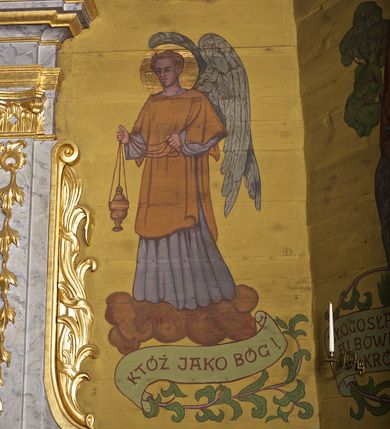 Zdjęcie nr 6: Ściany kościoła dekorują przedstawienia świętych: św. Stanisław w stroju pontyfikalnym z pastorałem, wskrzeszający Piotrowina. Poniżej na banderoli napis „BŁOGOSŁAWIENI KTÓRZY ŁAKNĄ / I PRAGNĄ SPRAWIEDLIWOŚCI”; św. Jadwiga w koronie i płaszczu podszytym gronostajem, trzymająca skrzyneczkę z klejnotami oraz krzyż z herbami Polski i Litwy. Na banderoli napis „BŁOGOSŁAWIENI / POKÓJ CZYNIĄCY”; św. Jan Kanty błogosławiący dziewczynę z dzbanem podpisany „BŁOGOSŁAWIENI / MIŁOSIERNI”; św. w habicie, z krzyżem w ręce i w asyście dwóch aniołów - jednego z palmą męczeństwa, drugiego z płonącą pochodnią, pod nimi napis „BŁOGOSŁAWIENI KTÓRZY / CIERPIĄ PRZEŚLADOWANIA DLA SPRAWIEDLIWOŚCI”; Chrystus z sercem gorejącym. Po jego prawej stronie klęczący mężczyzna, po lewej dwie owieczki nad strumieniem. Scena podpisana: „KTÓRZY PRACUJECIE I / OBCIĄŻENI JESTEŚCIE / A JA WAS OCHŁODZĘ”; archanioł Gabriel z lilią powyżej napisu  „ZDROWAŚ MARIO”; archanioł Michał z trybularzem, ponad napisem „KTÓŻ JAK BÓG!”; św. Franciszek na tle przyrody. Jest ubrany w habit franciszkański, na głowie ma kaptur. Przy prawej nodze świętego wilk, w jeziorze ryby, na niebie ptaki. Na banderoli napis „BŁOGOSŁAWIENI UBODZY DUCHEM / ALBOWIEM TAKOWYCH JEST / KRÓLESTWO NIEBIESKIE”; św. Izydor Oracz ukazany w towarzystwie anioła orającego na polu na tle dzwonnicy. Poniżej napis „BŁOGOSŁAWIENI CISI / ALBOWIEM ONI / POSIĄDĄ ZIEMIĘ”. Poniżej postaci świętych fryz z przedstawieniem 14 stacji drogi krzyżowej na błękitnym tle. Na stropie nawy i prezbiterium, na błękitnym tle, wśród kwiatowego ornamentu na środku ukazany Chrystus Ukrzyżowany ponad kielichem, gołębica Ducha Świętego i koronowana Maria. Po ich obu stronach stoją święci mężowie i niewiasty z atrybutami. W nawie w kolejności do środka: św. Wojciech (?), św. Jacek z figurą Matki Boskiej i monstrancją, klęczący św. Kazimierz w stroju książęcym z lilią, św. Agnieszka z barankiem i św. Karolina Kózkówna z różańcem, klęcząca św. Rozalia z różami, św. Klara z cyborium, św. Weronika z chustą z wizerunkiem Chrystusa, klęcząca św. Cecylia z lirą, św. Józef z lilią, św. Paweł z mieczem, klęczący św. Jan Chrzciciel z krzyżem. W prezbiterium przedstawiono 12 apostołów, niektórzy z atrybutmi, które ich jednoznacznie identyfilują, np. św. Andrzej z krzyżem w kształcie litery X, inni z księgami lub zwojami.  