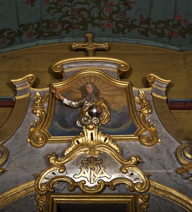 Zdjęcie nr 8: Ołtarz architektoniczny, jednoosiowy, jednokondygnacyjny. Mensa prostopadłościenna z antepedium haftowanym bogatą dekoracją kwiatową, z centralnie umieszczonym kielichem w otoczeniu winnej latorośli. Na nim tabernakulum w formie zbliżonej do prostopadłościennej skrzynki o wypukłej ściance frontowej na tle ścianki z tronem wystawienia ustawionej na cokole i ujętej spływami wolutowymi. Drzwiczki tabernakulum dekorowane krzyżem z glorią między literami „Α” i „Ω”. Tron wystawienia złocony, dekorowany kwiatem między stylizowanymi liśćmi i ujęty od góry muszlą palmetową. Tron ujmują lizeny przedzielone i zwieńczone gzymsem ustawionym skośnie i zakończonym od wewnętrznej strony wolutami. Gzyms nad tronem wystawienia wyniesiony, w formie łuku nadwieszonego. Na jego zewnętrznych częściach posadowiono figurki klęczących i modlących się aniołków. Nastawa ujęta parą zdwojonych pilastrów na cokołach, o głowicach korynckich, z impostami z dekoracją w formie festonów z rocaille’em i liśćmi. Uszy w formie spływów wolutowych z dekoracją liściastą. W centrum pole obrazowe z wnęką o profilowanej ramie w kształcie stojącego prostokąta ujętego w spływy wolutowe i festony, zwieńczone wydatnym kartuszem dekorowanym rocaille’em, z monogramem maryjnym. W nim ukazana Matka Boska Anielska przesłaniana obrazem „Wszyscy Święci” wzorowanym na obrazie Rafaela. Retabulum przedzielone gzymsem wyniesionym w łuk ponad polem centralnym. Zwieńczenie w formie zbliżonej do prostokąta, rozszerzające się ku dołowi, ujęte w esowate pilastry przechodzące w woluty, zamknięte łukiem odcinkowym zakończonym wolutami. Całość wieńczy krzyż z rozetą na skrzyżowaniu ramion. W zwieńczeniu wklęsło-wypukłe pole obrazowe z płaskorzeźbionym popiersiem Boga Ojca na tle nieba. Na impostach leżące figury aniołów. Struktura polichromowana, marmoryzowana w odcieniu jasnoszarym, profile, ornamenty i dekoracje złocone i srebrzone. 