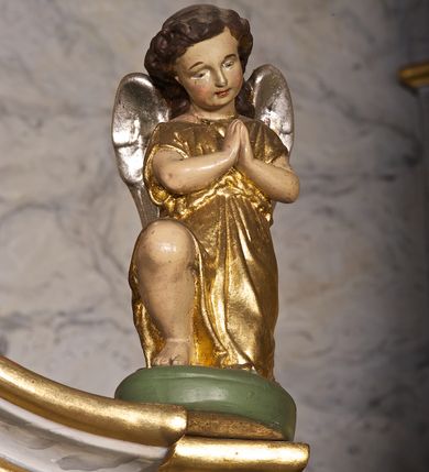 Zdjęcie nr 14: Ołtarz architektoniczny, jednoosiowy, jednokondygnacyjny. Mensa prostopadłościenna z antepedium haftowanym bogatą dekoracją kwiatową, z centralnie umieszczonym kielichem w otoczeniu winnej latorośli. Na nim tabernakulum w formie zbliżonej do prostopadłościennej skrzynki o wypukłej ściance frontowej na tle ścianki z tronem wystawienia ustawionej na cokole i ujętej spływami wolutowymi. Drzwiczki tabernakulum dekorowane krzyżem z glorią między literami „Α” i „Ω”. Tron wystawienia złocony, dekorowany kwiatem między stylizowanymi liśćmi i ujęty od góry muszlą palmetową. Tron ujmują lizeny przedzielone i zwieńczone gzymsem ustawionym skośnie i zakończonym od wewnętrznej strony wolutami. Gzyms nad tronem wystawienia wyniesiony, w formie łuku nadwieszonego. Na jego zewnętrznych częściach posadowiono figurki klęczących i modlących się aniołków. Nastawa ujęta parą zdwojonych pilastrów na cokołach, o głowicach korynckich, z impostami z dekoracją w formie festonów z rocaille’em i liśćmi. Uszy w formie spływów wolutowych z dekoracją liściastą. W centrum pole obrazowe z wnęką o profilowanej ramie w kształcie stojącego prostokąta ujętego w spływy wolutowe i festony, zwieńczone wydatnym kartuszem dekorowanym rocaille’em, z monogramem maryjnym. W nim ukazana Matka Boska Anielska przesłaniana obrazem „Wszyscy Święci” wzorowanym na obrazie Rafaela. Retabulum przedzielone gzymsem wyniesionym w łuk ponad polem centralnym. Zwieńczenie w formie zbliżonej do prostokąta, rozszerzające się ku dołowi, ujęte w esowate pilastry przechodzące w woluty, zamknięte łukiem odcinkowym zakończonym wolutami. Całość wieńczy krzyż z rozetą na skrzyżowaniu ramion. W zwieńczeniu wklęsło-wypukłe pole obrazowe z płaskorzeźbionym popiersiem Boga Ojca na tle nieba. Na impostach leżące figury aniołów. Struktura polichromowana, marmoryzowana w odcieniu jasnoszarym, profile, ornamenty i dekoracje złocone i srebrzone. 