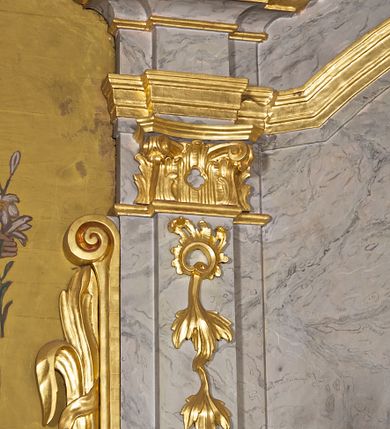 Zdjęcie nr 3: Ołtarz architektoniczny, jednoosiowy, jednokondygnacyjny. Mensa prostopadłościenna z antepedium haftowanym bogatą dekoracją kwiatową, z centralnie umieszczonym kielichem w otoczeniu winnej latorośli. Na nim tabernakulum w formie zbliżonej do prostopadłościennej skrzynki o wypukłej ściance frontowej na tle ścianki z tronem wystawienia ustawionej na cokole i ujętej spływami wolutowymi. Drzwiczki tabernakulum dekorowane krzyżem z glorią między literami „Α” i „Ω”. Tron wystawienia złocony, dekorowany kwiatem między stylizowanymi liśćmi i ujęty od góry muszlą palmetową. Tron ujmują lizeny przedzielone i zwieńczone gzymsem ustawionym skośnie i zakończonym od wewnętrznej strony wolutami. Gzyms nad tronem wystawienia wyniesiony, w formie łuku nadwieszonego. Na jego zewnętrznych częściach posadowiono figurki klęczących i modlących się aniołków. Nastawa ujęta parą zdwojonych pilastrów na cokołach, o głowicach korynckich, z impostami z dekoracją w formie festonów z rocaille’em i liśćmi. Uszy w formie spływów wolutowych z dekoracją liściastą. W centrum pole obrazowe z wnęką o profilowanej ramie w kształcie stojącego prostokąta ujętego w spływy wolutowe i festony, zwieńczone wydatnym kartuszem dekorowanym rocaille’em, z monogramem maryjnym. W nim ukazana Matka Boska Anielska przesłaniana obrazem „Wszyscy Święci” wzorowanym na obrazie Rafaela. Retabulum przedzielone gzymsem wyniesionym w łuk ponad polem centralnym. Zwieńczenie w formie zbliżonej do prostokąta, rozszerzające się ku dołowi, ujęte w esowate pilastry przechodzące w woluty, zamknięte łukiem odcinkowym zakończonym wolutami. Całość wieńczy krzyż z rozetą na skrzyżowaniu ramion. W zwieńczeniu wklęsło-wypukłe pole obrazowe z płaskorzeźbionym popiersiem Boga Ojca na tle nieba. Na impostach leżące figury aniołów. Struktura polichromowana, marmoryzowana w odcieniu jasnoszarym, profile, ornamenty i dekoracje złocone i srebrzone. 