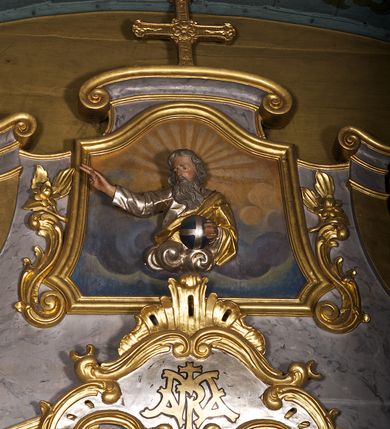 Zdjęcie nr 10: Ołtarz architektoniczny, jednoosiowy, jednokondygnacyjny. Mensa prostopadłościenna z antepedium haftowanym bogatą dekoracją kwiatową, z centralnie umieszczonym kielichem w otoczeniu winnej latorośli. Na nim tabernakulum w formie zbliżonej do prostopadłościennej skrzynki o wypukłej ściance frontowej na tle ścianki z tronem wystawienia ustawionej na cokole i ujętej spływami wolutowymi. Drzwiczki tabernakulum dekorowane krzyżem z glorią między literami „Α” i „Ω”. Tron wystawienia złocony, dekorowany kwiatem między stylizowanymi liśćmi i ujęty od góry muszlą palmetową. Tron ujmują lizeny przedzielone i zwieńczone gzymsem ustawionym skośnie i zakończonym od wewnętrznej strony wolutami. Gzyms nad tronem wystawienia wyniesiony, w formie łuku nadwieszonego. Na jego zewnętrznych częściach posadowiono figurki klęczących i modlących się aniołków. Nastawa ujęta parą zdwojonych pilastrów na cokołach, o głowicach korynckich, z impostami z dekoracją w formie festonów z rocaille’em i liśćmi. Uszy w formie spływów wolutowych z dekoracją liściastą. W centrum pole obrazowe z wnęką o profilowanej ramie w kształcie stojącego prostokąta ujętego w spływy wolutowe i festony, zwieńczone wydatnym kartuszem dekorowanym rocaille’em, z monogramem maryjnym. W nim ukazana Matka Boska Anielska przesłaniana obrazem „Wszyscy Święci” wzorowanym na obrazie Rafaela. Retabulum przedzielone gzymsem wyniesionym w łuk ponad polem centralnym. Zwieńczenie w formie zbliżonej do prostokąta, rozszerzające się ku dołowi, ujęte w esowate pilastry przechodzące w woluty, zamknięte łukiem odcinkowym zakończonym wolutami. Całość wieńczy krzyż z rozetą na skrzyżowaniu ramion. W zwieńczeniu wklęsło-wypukłe pole obrazowe z płaskorzeźbionym popiersiem Boga Ojca na tle nieba. Na impostach leżące figury aniołów. Struktura polichromowana, marmoryzowana w odcieniu jasnoszarym, profile, ornamenty i dekoracje złocone i srebrzone. 