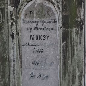 Zdjęcie nr 1: Nagrobek kamienny na cokole, w formie prostopadłościanu o fazowanych bokach, zakończony wyniesionym, uproszczonym trójkątnym przyczółkiem. W zwieńczeniu owalny medalion, w którym mógł znajdować się wizerunek Chrystusa, obecnie bardzo zniszczony, ujęty wieńcem (?). Poniżej płycina zamknięta łukiem półkolistym i inskrypcją „D(EO) O(PTIMO) M(AXIMO) / Tu spoczywają zwłoki / s(więtej) p(amięci) Wicentego / MOKSY / urodzonego [...] / * 1800 [...] / [...] 1870 [...] / [...] do Boga”. Powyżej płyciny rzeźbiona głowa w owalnym medalionie. Nagrobek był ziweńczony krzyżem, obecnie ułamanym, leżącym obok cokołu. Na przedniej ścianie, na cokole sygnatura kamieniarza F. HOCHSTIM.