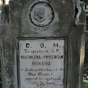Zdjęcie nr 1: Nagrobek kamienny na cokole, w formie prostopadłościanu o fazowanych bokach, zakończony wyniesionym, uproszczonym trójkątnym przyczółkiem. W zwieńczeniu ślad po owalnym medalionie, poniżej na trzonie prostokątna, fazowana płycina z inskrypcją: „D(EO) O(PTIMO) M(AXIMO)/ Tu spoczywa S(więtej). P(amięci) / MAGDALENA z KMIECIKÓW / MOKSINA / + 1 Grudnia 1873 r(oku) licząc lat - 64 / Mąż Wicenty / pomnik ten wystawił. / Pokój Jej duszy.”. Nagrobek był najpewniej zwieńćzony krzyżem. Na przedniej ścianie na cokole podpis kamieniarza: „F. HOCHSTIM”.