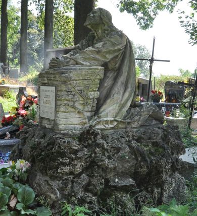 Zdjęcie nr 2: Nagrobek kamienny, wolnostojący z przedstawieniem modlitwy Chrystusa w Ogrójcu. Rzeźba posadowiona na bloku imitującym skały, na którym umieszczono Zbawiciela klęczącego przed pulpitem wybudowanym z kamieni. Chrystus złożone do modlitwy ręce wyciąga przed siebie i opiera na pulpicie, głowę ma uniesioną, spogląda w niebo. Ma podłużną twarz, na której maluje się wyraz rozpaczy, krótką brodę i długie włosy opadające puklami na ramiona i plecy. Jest ubrany w długą, przepasaną suknię i płaszcz. Na przedniej stronie pulpitu tablica z kutą, złoconą inskrypcją „ZA SPOKÓJ DUSZY ŚWIĘTEJ PAMIĘCI / JÓZEFA / GABUTA / UR(ODZONEGO) 2. VII 1910 ZM(ARŁEGO) 11. IV 1933. / PROSI O ZDROWAŚ MARIA”.