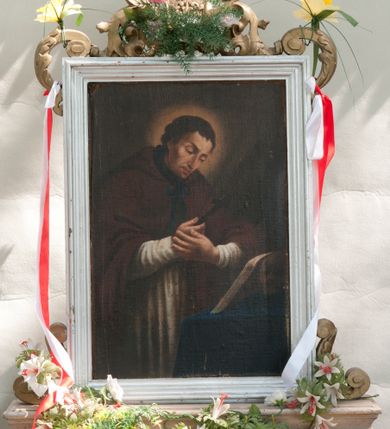 Zdjęcie nr 2: Pole obrazowe w kształcie stojącego prostokąta. Rama profilowana, ujęta w narożach wolutami z liśćmi akantu, zwieńczona monogramem maryjnym z krzyżem na podstawie z  wici akantowej. Obraz z wizerunkiem Jana Nepomucena, który z krzyżem w ręce pochyla się nad otwartą księgą i czaszką, leżącymi na stole, nakrytym niebieską tkaniną. Jest ubrany w białą komżę i ciemnobrązową almucję, zawiązaną pod szyją niebieską taśmą. Kolorystyka ciemna, gama barwna oparta na brązach. Na odwrocie Obraz Matki Boskiej w typie Matki Boskiej Częstochowskiej utrzymany w ciemnej kolorystyce. Maria została ukazana w półpostaci, z Dzieciątkiem na lewym ramieniu, wskazując na nie drugą ręką. Patrzy na widza, ma duże, ciemne oczy, wąski nos i niewielkie usta. Jest ubrana z ciemną suknię w z wąskimi rękawami, na to szerszą, czerwoną, a po wierzchu ma jasnobeżowy maforion dekorowany schematycznym ornamentem roślinnym. Dzieciątko prawą rękę unosi w geście błogosławieństwa, w lewej trzyma zamkniętą książeczkę. Ma owalną twarz z wysokim czołem, ciemne oczy, niewielki nos i usta. Jest ubrane w długą, jasną, dekorowaną drobnym ornamentem sukienkę. Obie postacie mają na głowach zamknięte korony, a wokół złocone nimby i 12 gwiazdek. 
Feretron dwustronny, z podstawą prostopadłościenną, z otworami na drążki.
Rama i podstawa malowane na biało, ornamenty złocone. 
