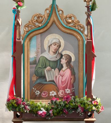 Zdjęcie nr 2: Feretron w formie obrazu w kształcie stojącego prostokąta w neogotyckiej ramie utworzonej z flankujących przedstawienie pinakli zakończonych kwiatonami. Zwieńczenie w formie łuku w ośli grzbiet dekorowanego astwerkiem. Na awersie przedstawienie Immaculaty wzorowanej na obrazie autorstwa Bartolomea Estebana Murilla. Maria została przedstawiona całopostaciowo, zwrócona w trzech czwartych w prawo, z głową odwróconą w przeciwną stronę. Stoi na półksiężycu, ręce składa na piersi. Jest ubrana w białą suknię i niebieski płaszcz. Wokół niej fruwają ukazane w przeróżnych pozach aniołki osłonięte kolorowymi szarfami. Tło stanowią jasne obłoki. Na rewersie przedstawienie św. Anny nauczającej małą Marię. W centrum kompozycji św. Anna, która siedzi na krześle, w prawej ręce trzyma opartą na kolanach otwartą książkę, a lewą obejmuje Marię. Ma owalną twarz o skupionym wyrazie osadzoną na szerokiej szyi. Jest ubrana w zielono-brązową suknię i niebieski płaszcz, głowę ma owiniętą białą chustą. Maria stoi, ma uniesiony wzrok, ręce składa w geście modlitwy. Jest ubrana w różową suknię z szerokimi rękawami. Wokół ich głów nimby, w tle szara ściana; przy lewej krawędzi widoczny fragment okna, przez które widać szeroki, górzysty krajobraz. 
Rama polichromowana na kolor niebieski i brązowy, złocona. 
