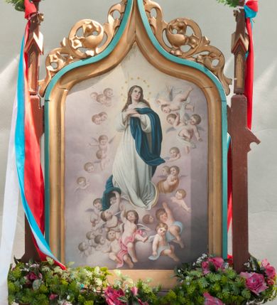 Zdjęcie nr 1: Feretron w formie obrazu w kształcie stojącego prostokąta w neogotyckiej ramie utworzonej z flankujących przedstawienie pinakli zakończonych kwiatonami. Zwieńczenie w formie łuku w ośli grzbiet dekorowanego astwerkiem. Na awersie przedstawienie Immaculaty wzorowanej na obrazie autorstwa Bartolomea Estebana Murilla. Maria została przedstawiona całopostaciowo, zwrócona w trzech czwartych w prawo, z głową odwróconą w przeciwną stronę. Stoi na półksiężycu, ręce składa na piersi. Jest ubrana w białą suknię i niebieski płaszcz. Wokół niej fruwają ukazane w przeróżnych pozach aniołki osłonięte kolorowymi szarfami. Tło stanowią jasne obłoki. Na rewersie przedstawienie św. Anny nauczającej małą Marię. W centrum kompozycji św. Anna, która siedzi na krześle, w prawej ręce trzyma opartą na kolanach otwartą książkę, a lewą obejmuje Marię. Ma owalną twarz o skupionym wyrazie osadzoną na szerokiej szyi. Jest ubrana w zielono-brązową suknię i niebieski płaszcz, głowę ma owiniętą białą chustą. Maria stoi, ma uniesiony wzrok, ręce składa w geście modlitwy. Jest ubrana w różową suknię z szerokimi rękawami. Wokół ich głów nimby, w tle szara ściana; przy lewej krawędzi widoczny fragment okna, przez które widać szeroki, górzysty krajobraz. 
Rama polichromowana na kolor niebieski i brązowy, złocona. 
