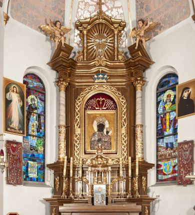Zdjęcie nr 1: Ołtarz przyścienny, architektoniczny, jednoosiowy, jednokondygnacyjny ze zwieńczeniem. Mensa drewniana w kształcie prostopadłościennej skrzyni z narożami lekko wysuniętymi przed jej lico. Antependium drewniane z umieszczoną w centrum prostokątną płyciną z płaskorzeźbioną sceną Ostatniej Wieczerzy według Leonarda da Vinci. Po bokach po dwie mniejsze płyciny w kształcie prostokąta stojącego wypełnione płaskorzeźbioną, złoconą dekoracją z winnym gronem, kłosami, kwiatami oraz muszlą palmetową. 
Tabernakulum w kształcie prostopadłościennej, obitej metalową blachą skrzynki, dwudrzwiowe. Na drzwiczkach odlewana dekoracja z kłosów i winnych gron, powyżej gorejące serce. Tabernakulum ujęte drewnianym tronem wystawienia w formie ażurowej kolumnady na planie półkola. Zwieńczone ażurowymi wolutami tworzącymi formę baldachimu. U szczytu korona zamknięta, u jej podstawy Baranek Apokaliptyczny. 
Retabulum ustawione na wysokim cokole z bokami zwróconymi pod kątem 45 stopni, zwieńczonym wydatnym profilowanym gzymsem. Na ścianach cokołów uskrzydlone główki aniołów z podwieszonym ornamentem o motywach cęgowych i roślinnych. Kondygnacja flankowana jest parą kolumn podtrzymujących niepełne belkowanie. Kolumny o kapitelach kompozytowych, marmoryzowanych trzonach, z nałożoną do połowy dekoracją w formie ornamentalnej wici roślinnej złożonej z motywów akantu, rocaille'u, palmety i ornamentu cęgowego. Na gzymsie fragmenty przerwanego trójkątnego przyczółka, na których siedzą pełnoplastyczne figury aniołków. Pole główne ołtarza o lekko zaoblonych narożach, w jego centrum złocona, profilowana rama w otoku z cierniowej korony, o kształcie prostokąta stojącego zakończonego półkoliście. Pośrodku obraz Matki Boskiej Częstochowskiej oraz obraz Ukrzyżowanie na zasuwie, ponad którym umieszczona jest płaskorzeźba Boga Ojca. Powyżej, na osi ołtarza złocona korona z krzyżykiem. 
Zwieńczenie ujęte jest kolumnami analogicznymi jak w kondygnacji dźwigającymi niepełne, przełamane na osi podpór belkowanie o linii wklęsło-wypukłej. W polu promienista gloria z gołębicą Ducha Świętego na tle obłoków. Po bokach zwieńczenia znajdują się spływy wolutowe dekorowane kwiatami. U szczytu krzyż wyrastający z palmety. Ołtarz malowany na kolor brązowy, złocenia w partiach profili elementów architektonicznych i ornamentów złocone, detale srebrzone.