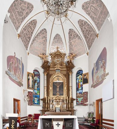 Zdjęcie nr 2: Ołtarz przyścienny, architektoniczny, jednoosiowy, jednokondygnacyjny ze zwieńczeniem. Mensa drewniana w kształcie prostopadłościennej skrzyni z narożami lekko wysuniętymi przed jej lico. Antependium drewniane z umieszczoną w centrum prostokątną płyciną z płaskorzeźbioną sceną Ostatniej Wieczerzy według Leonarda da Vinci. Po bokach po dwie mniejsze płyciny w kształcie prostokąta stojącego wypełnione płaskorzeźbioną, złoconą dekoracją z winnym gronem, kłosami, kwiatami oraz muszlą palmetową. 
Tabernakulum w kształcie prostopadłościennej, obitej metalową blachą skrzynki, dwudrzwiowe. Na drzwiczkach odlewana dekoracja z kłosów i winnych gron, powyżej gorejące serce. Tabernakulum ujęte drewnianym tronem wystawienia w formie ażurowej kolumnady na planie półkola. Zwieńczone ażurowymi wolutami tworzącymi formę baldachimu. U szczytu korona zamknięta, u jej podstawy Baranek Apokaliptyczny. 
Retabulum ustawione na wysokim cokole z bokami zwróconymi pod kątem 45 stopni, zwieńczonym wydatnym profilowanym gzymsem. Na ścianach cokołów uskrzydlone główki aniołów z podwieszonym ornamentem o motywach cęgowych i roślinnych. Kondygnacja flankowana jest parą kolumn podtrzymujących niepełne belkowanie. Kolumny o kapitelach kompozytowych, marmoryzowanych trzonach, z nałożoną do połowy dekoracją w formie ornamentalnej wici roślinnej złożonej z motywów akantu, rocaille'u, palmety i ornamentu cęgowego. Na gzymsie fragmenty przerwanego trójkątnego przyczółka, na których siedzą pełnoplastyczne figury aniołków. Pole główne ołtarza o lekko zaoblonych narożach, w jego centrum złocona, profilowana rama w otoku z cierniowej korony, o kształcie prostokąta stojącego zakończonego półkoliście. Pośrodku obraz Matki Boskiej Częstochowskiej oraz obraz Ukrzyżowanie na zasuwie, ponad którym umieszczona jest płaskorzeźba Boga Ojca. Powyżej, na osi ołtarza złocona korona z krzyżykiem. 
Zwieńczenie ujęte jest kolumnami analogicznymi jak w kondygnacji dźwigającymi niepełne, przełamane na osi podpór belkowanie o linii wklęsło-wypukłej. W polu promienista gloria z gołębicą Ducha Świętego na tle obłoków. Po bokach zwieńczenia znajdują się spływy wolutowe dekorowane kwiatami. U szczytu krzyż wyrastający z palmety. Ołtarz malowany na kolor brązowy, złocenia w partiach profili elementów architektonicznych i ornamentów złocone, detale srebrzone.