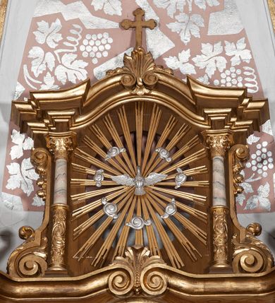 Zdjęcie nr 17: Ołtarz przyścienny, architektoniczny, jednoosiowy, jednokondygnacyjny ze zwieńczeniem. Mensa drewniana w kształcie prostopadłościennej skrzyni z narożami lekko wysuniętymi przed jej lico. Antependium drewniane z umieszczoną w centrum prostokątną płyciną z płaskorzeźbioną sceną Ostatniej Wieczerzy według Leonarda da Vinci. Po bokach po dwie mniejsze płyciny w kształcie prostokąta stojącego wypełnione płaskorzeźbioną, złoconą dekoracją z winnym gronem, kłosami, kwiatami oraz muszlą palmetową. 
Tabernakulum w kształcie prostopadłościennej, obitej metalową blachą skrzynki, dwudrzwiowe. Na drzwiczkach odlewana dekoracja z kłosów i winnych gron, powyżej gorejące serce. Tabernakulum ujęte drewnianym tronem wystawienia w formie ażurowej kolumnady na planie półkola. Zwieńczone ażurowymi wolutami tworzącymi formę baldachimu. U szczytu korona zamknięta, u jej podstawy Baranek Apokaliptyczny. 
Retabulum ustawione na wysokim cokole z bokami zwróconymi pod kątem 45 stopni, zwieńczonym wydatnym profilowanym gzymsem. Na ścianach cokołów uskrzydlone główki aniołów z podwieszonym ornamentem o motywach cęgowych i roślinnych. Kondygnacja flankowana jest parą kolumn podtrzymujących niepełne belkowanie. Kolumny o kapitelach kompozytowych, marmoryzowanych trzonach, z nałożoną do połowy dekoracją w formie ornamentalnej wici roślinnej złożonej z motywów akantu, rocaille&#039;u, palmety i ornamentu cęgowego. Na gzymsie fragmenty przerwanego trójkątnego przyczółka, na których siedzą pełnoplastyczne figury aniołków. Pole główne ołtarza o lekko zaoblonych narożach, w jego centrum złocona, profilowana rama w otoku z cierniowej korony, o kształcie prostokąta stojącego zakończonego półkoliście. Pośrodku obraz Matki Boskiej Częstochowskiej oraz obraz Ukrzyżowanie na zasuwie, ponad którym umieszczona jest płaskorzeźba Boga Ojca. Powyżej, na osi ołtarza złocona korona z krzyżykiem. 
Zwieńczenie ujęte jest kolumnami analogicznymi jak w kondygnacji dźwigającymi niepełne, przełamane na osi podpór belkowanie o linii wklęsło-wypukłej. W polu promienista gloria z gołębicą Ducha Świętego na tle obłoków. Po bokach zwieńczenia znajdują się spływy wolutowe dekorowane kwiatami. U szczytu krzyż wyrastający z palmety. Ołtarz malowany na kolor brązowy, złocenia w partiach profili elementów architektonicznych i ornamentów złocone, detale srebrzone.