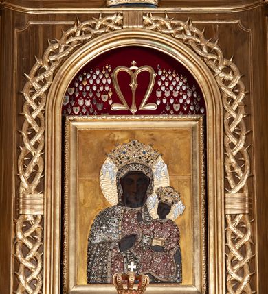 Zdjęcie nr 16: Ołtarz przyścienny, architektoniczny, jednoosiowy, jednokondygnacyjny ze zwieńczeniem. Mensa drewniana w kształcie prostopadłościennej skrzyni z narożami lekko wysuniętymi przed jej lico. Antependium drewniane z umieszczoną w centrum prostokątną płyciną z płaskorzeźbioną sceną Ostatniej Wieczerzy według Leonarda da Vinci. Po bokach po dwie mniejsze płyciny w kształcie prostokąta stojącego wypełnione płaskorzeźbioną, złoconą dekoracją z winnym gronem, kłosami, kwiatami oraz muszlą palmetową. 
Tabernakulum w kształcie prostopadłościennej, obitej metalową blachą skrzynki, dwudrzwiowe. Na drzwiczkach odlewana dekoracja z kłosów i winnych gron, powyżej gorejące serce. Tabernakulum ujęte drewnianym tronem wystawienia w formie ażurowej kolumnady na planie półkola. Zwieńczone ażurowymi wolutami tworzącymi formę baldachimu. U szczytu korona zamknięta, u jej podstawy Baranek Apokaliptyczny. 
Retabulum ustawione na wysokim cokole z bokami zwróconymi pod kątem 45 stopni, zwieńczonym wydatnym profilowanym gzymsem. Na ścianach cokołów uskrzydlone główki aniołów z podwieszonym ornamentem o motywach cęgowych i roślinnych. Kondygnacja flankowana jest parą kolumn podtrzymujących niepełne belkowanie. Kolumny o kapitelach kompozytowych, marmoryzowanych trzonach, z nałożoną do połowy dekoracją w formie ornamentalnej wici roślinnej złożonej z motywów akantu, rocaille&#039;u, palmety i ornamentu cęgowego. Na gzymsie fragmenty przerwanego trójkątnego przyczółka, na których siedzą pełnoplastyczne figury aniołków. Pole główne ołtarza o lekko zaoblonych narożach, w jego centrum złocona, profilowana rama w otoku z cierniowej korony, o kształcie prostokąta stojącego zakończonego półkoliście. Pośrodku obraz Matki Boskiej Częstochowskiej oraz obraz Ukrzyżowanie na zasuwie, ponad którym umieszczona jest płaskorzeźba Boga Ojca. Powyżej, na osi ołtarza złocona korona z krzyżykiem. 
Zwieńczenie ujęte jest kolumnami analogicznymi jak w kondygnacji dźwigającymi niepełne, przełamane na osi podpór belkowanie o linii wklęsło-wypukłej. W polu promienista gloria z gołębicą Ducha Świętego na tle obłoków. Po bokach zwieńczenia znajdują się spływy wolutowe dekorowane kwiatami. U szczytu krzyż wyrastający z palmety. Ołtarz malowany na kolor brązowy, złocenia w partiach profili elementów architektonicznych i ornamentów złocone, detale srebrzone.