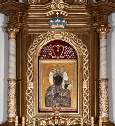 Zdjęcie nr 15: Ołtarz przyścienny, architektoniczny, jednoosiowy, jednokondygnacyjny ze zwieńczeniem. Mensa drewniana w kształcie prostopadłościennej skrzyni z narożami lekko wysuniętymi przed jej lico. Antependium drewniane z umieszczoną w centrum prostokątną płyciną z płaskorzeźbioną sceną Ostatniej Wieczerzy według Leonarda da Vinci. Po bokach po dwie mniejsze płyciny w kształcie prostokąta stojącego wypełnione płaskorzeźbioną, złoconą dekoracją z winnym gronem, kłosami, kwiatami oraz muszlą palmetową. 
Tabernakulum w kształcie prostopadłościennej, obitej metalową blachą skrzynki, dwudrzwiowe. Na drzwiczkach odlewana dekoracja z kłosów i winnych gron, powyżej gorejące serce. Tabernakulum ujęte drewnianym tronem wystawienia w formie ażurowej kolumnady na planie półkola. Zwieńczone ażurowymi wolutami tworzącymi formę baldachimu. U szczytu korona zamknięta, u jej podstawy Baranek Apokaliptyczny. 
Retabulum ustawione na wysokim cokole z bokami zwróconymi pod kątem 45 stopni, zwieńczonym wydatnym profilowanym gzymsem. Na ścianach cokołów uskrzydlone główki aniołów z podwieszonym ornamentem o motywach cęgowych i roślinnych. Kondygnacja flankowana jest parą kolumn podtrzymujących niepełne belkowanie. Kolumny o kapitelach kompozytowych, marmoryzowanych trzonach, z nałożoną do połowy dekoracją w formie ornamentalnej wici roślinnej złożonej z motywów akantu, rocaille'u, palmety i ornamentu cęgowego. Na gzymsie fragmenty przerwanego trójkątnego przyczółka, na których siedzą pełnoplastyczne figury aniołków. Pole główne ołtarza o lekko zaoblonych narożach, w jego centrum złocona, profilowana rama w otoku z cierniowej korony, o kształcie prostokąta stojącego zakończonego półkoliście. Pośrodku obraz Matki Boskiej Częstochowskiej oraz obraz Ukrzyżowanie na zasuwie, ponad którym umieszczona jest płaskorzeźba Boga Ojca. Powyżej, na osi ołtarza złocona korona z krzyżykiem. 
Zwieńczenie ujęte jest kolumnami analogicznymi jak w kondygnacji dźwigającymi niepełne, przełamane na osi podpór belkowanie o linii wklęsło-wypukłej. W polu promienista gloria z gołębicą Ducha Świętego na tle obłoków. Po bokach zwieńczenia znajdują się spływy wolutowe dekorowane kwiatami. U szczytu krzyż wyrastający z palmety. Ołtarz malowany na kolor brązowy, złocenia w partiach profili elementów architektonicznych i ornamentów złocone, detale srebrzone.