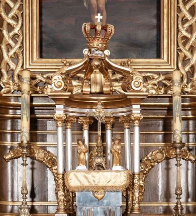 Zdjęcie nr 6: Ołtarz przyścienny, architektoniczny, jednoosiowy, jednokondygnacyjny ze zwieńczeniem. Mensa drewniana w kształcie prostopadłościennej skrzyni z narożami lekko wysuniętymi przed jej lico. Antependium drewniane z umieszczoną w centrum prostokątną płyciną z płaskorzeźbioną sceną Ostatniej Wieczerzy według Leonarda da Vinci. Po bokach po dwie mniejsze płyciny w kształcie prostokąta stojącego wypełnione płaskorzeźbioną, złoconą dekoracją z winnym gronem, kłosami, kwiatami oraz muszlą palmetową. 
Tabernakulum w kształcie prostopadłościennej, obitej metalową blachą skrzynki, dwudrzwiowe. Na drzwiczkach odlewana dekoracja z kłosów i winnych gron, powyżej gorejące serce. Tabernakulum ujęte drewnianym tronem wystawienia w formie ażurowej kolumnady na planie półkola. Zwieńczone ażurowymi wolutami tworzącymi formę baldachimu. U szczytu korona zamknięta, u jej podstawy Baranek Apokaliptyczny. 
Retabulum ustawione na wysokim cokole z bokami zwróconymi pod kątem 45 stopni, zwieńczonym wydatnym profilowanym gzymsem. Na ścianach cokołów uskrzydlone główki aniołów z podwieszonym ornamentem o motywach cęgowych i roślinnych. Kondygnacja flankowana jest parą kolumn podtrzymujących niepełne belkowanie. Kolumny o kapitelach kompozytowych, marmoryzowanych trzonach, z nałożoną do połowy dekoracją w formie ornamentalnej wici roślinnej złożonej z motywów akantu, rocaille&#039;u, palmety i ornamentu cęgowego. Na gzymsie fragmenty przerwanego trójkątnego przyczółka, na których siedzą pełnoplastyczne figury aniołków. Pole główne ołtarza o lekko zaoblonych narożach, w jego centrum złocona, profilowana rama w otoku z cierniowej korony, o kształcie prostokąta stojącego zakończonego półkoliście. Pośrodku obraz Matki Boskiej Częstochowskiej oraz obraz Ukrzyżowanie na zasuwie, ponad którym umieszczona jest płaskorzeźba Boga Ojca. Powyżej, na osi ołtarza złocona korona z krzyżykiem. 
Zwieńczenie ujęte jest kolumnami analogicznymi jak w kondygnacji dźwigającymi niepełne, przełamane na osi podpór belkowanie o linii wklęsło-wypukłej. W polu promienista gloria z gołębicą Ducha Świętego na tle obłoków. Po bokach zwieńczenia znajdują się spływy wolutowe dekorowane kwiatami. U szczytu krzyż wyrastający z palmety. Ołtarz malowany na kolor brązowy, złocenia w partiach profili elementów architektonicznych i ornamentów złocone, detale srebrzone.