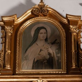 Zdjęcie nr 1: Obraz w kształcie stojącego prostokąta zamkniętego półkoliście, w złoconej, profilowanej ramie. W centrum postać św. Teresy Mniejszej ukazanej w półpostaci, zwróconej delikatnie w lewo. Lewą ręką tuli do siebie krucyfiks, z którego opadają płatki róż, w prawej trzyma różę. Twarz o młodzieńczych i delikatnych rysach. Święta jest ubrana w habit karmelitański. Głowa otoczona kolistym nimbem. Z lewej strony świętej, z góry pada snop światła. Tło jednolite, zielono-błękitne.