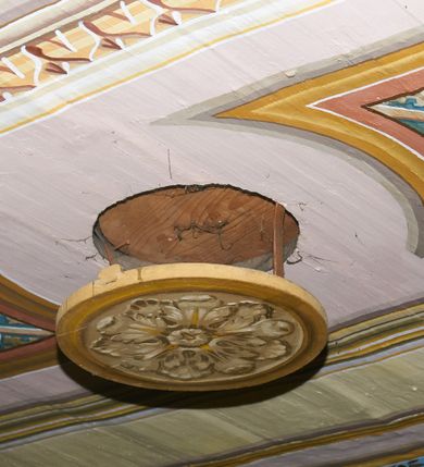 Zdjęcie nr 50: Polichromia ścian kościoła odpowiada podziałom architektonicznym wnętrza wydzielonym przez pilastry. Malowany zielony cokół w jednej czwartej wysokości ścian wyodrębniony jest pasem ornamentu geometrycznego, w nawie w jego polu znajdują się żółte prostokąty z dekoracją geometryczną, w prezbiterium malowana jasnozielona tkanina z dwoma pasami ornamentu roślinnego, medalionami z monogramami Marii i koronami oraz z motywem lilii heraldycznych i rozet. Trzony pilastrów wnętrza bladożółte z malowanymi płycinami dekorowanymi kampanulami, głowice zdobione malowanym kimationem. Na osi pilastrów, w partii fryzu, na tle niebieskich prostokątów uskrzydlone główki anielskie, pomiędzy nimi fryz wypełniony różowo-pomarańczowymi malowanymi płycinami w błękitnym obramieniu o fantazyjnym wykroju, dekorowanymi kampanulami. Belkowanie zamknięte malowanym pasem ornamentu geometrycznego. W polach pomiędzy pilastrami malowane płyciny o fantazyjnym kształcie zbliżonym do prostokąta, ujęte ramą zakończoną kartuszem, ich pola wypełnione są dekoracją geometryczną składającą się z krzyży równoramiennych w glorii i rozet wykonanych techniką patronową. Otwory okienne ujęte są malowanymi, imitującymi profilowanie obramieniami, otwory drzwiowe iluzjonistycznymi portalami z uszakami: portal w nawie zwieńczony jest kartuszem, a portal w prezbiterium zwieńczony jest szczytem zamkniętym fragmentem gzymsu w formie łuku segmentowego nadwieszonego podtrzymywanym przez spływy wolutowe. Pod chórem muzycznym malowane tablice pamiątkowe ujęte ramą, na ścianie północnej z napisem: „Ecclam hanc sub titulo Assumptionis B.V. Mariae a strenuo / milite Wierzbięta in Branice et Ruszcza Haerede pimo in / Wola juxta fines villae Stryjów a D. 1386 fundatam decimis / ex praedio Branice a colonis Stryjów, Wola, cuius sors est Grabie / Szczurów Zymbrzeg et ibidem taberna cum duobus pratis ac lacubus / Orzek et Piotrek ditatam, proper alluviem Vistulae  curatus suus / in hunc locum, qui erat pratum Gruczyn, ecclae dotale transtulit, / Hac tandem post annos 356 collapsa, quam vides, A.R.D. Jacobus Cichoński, parochus Grabiensis a.D. 1742 in loco desolatae  novam erexit. / Consecravit Illmus ac Rmus Michaël Kunicki, Sufraganeus Eppus. / Cracoviensis, Abbas Clarae Tumbae a D. 1749. / Restauravit A.R.D. Josephus Raźny, parochus Grabiensis a.D. 1907. / e colectis parochianorum.”; na ścianie południowej z napisem: „Ku Pamięci! / Dzieci Moje Najmilsze - Ja Prastara Świątynia / Polska dziękuję Wam za serdeczną troskę / o mnie. Oto dzięki Waszym ofiarom Drodzy / Rodzice i Twoim wysiłkom Kochana Młodzieży / w r. 1959 odnowiło się moje oblicze - rozjaśniały /  moje ołtarze, a w r. 1960 zabrzmiał mój nowy / organ na większą chwałę Bożą. Ja Was za to / rodzę na nowo do życia łaski. Ja Was błogosławię / na życie rodzinne. Ja Was prowadzę ku Bogu. Ja / Was także żegnam poraz ostatni, gdy przechodzicie / z tego padołu płaczu do wieczności, aby / Was znowu powitać kiedyś w niebie.”. Na ścianie zachodniej, pod chórem, nad środkowym otworem przejściowym pozostałości dawnego iluzjonistycznego portalu z kartuszem herbowym. Na stropie prezbiterium wydzielone pole o kształcie powtarzającym plan prezbiterium, wewnątrz pole w formie kwadratu o wklęsłych narożach z wpisanym polem o fantazyjnym zarysie zbliżonym do owalu ze sceną Wniebowzięcia Najświętszej Marii Panny. W narożach owalne pola z czterema istotami apokaliptycznymi. Prosta belka tęczowa w kolorze zielonym, o profilowaniach w kolorze niebieskim i różowym, z napisem: „JEZU ZMIŁUJ SIĘ NAD NAMI”. Na stropie nawy prostokątne pole wydzielone grubym bladoróżowym obramieniem z płycinami o nieregularnym kształcie wypełnionymi kratką regencyjną i rozetami alternowanymi medalionami z rozetami, naroża dekorowane są wstęgą regencyjną i akantem. Wewnątrz pole o fantazyjnym wykroju zbliżonym do owalu ze sceną Koronacji Najświętszej Marii Panny, flankowane przez dwie malowane błękitne płyciny o nieregularnym kształcie wypełnione rozetkami. W narożach, w ozdobnych kartuszach herby Pogoni Litewskiej i Orła Białego.
