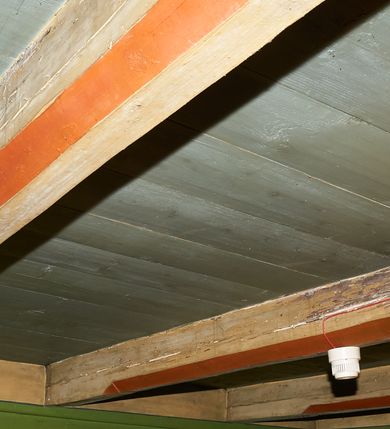 Zdjęcie nr 52: Polichromia ścian kościoła odpowiada podziałom architektonicznym wnętrza wydzielonym przez pilastry. Malowany zielony cokół w jednej czwartej wysokości ścian wyodrębniony jest pasem ornamentu geometrycznego, w nawie w jego polu znajdują się żółte prostokąty z dekoracją geometryczną, w prezbiterium malowana jasnozielona tkanina z dwoma pasami ornamentu roślinnego, medalionami z monogramami Marii i koronami oraz z motywem lilii heraldycznych i rozet. Trzony pilastrów wnętrza bladożółte z malowanymi płycinami dekorowanymi kampanulami, głowice zdobione malowanym kimationem. Na osi pilastrów, w partii fryzu, na tle niebieskich prostokątów uskrzydlone główki anielskie, pomiędzy nimi fryz wypełniony różowo-pomarańczowymi malowanymi płycinami w błękitnym obramieniu o fantazyjnym wykroju, dekorowanymi kampanulami. Belkowanie zamknięte malowanym pasem ornamentu geometrycznego. W polach pomiędzy pilastrami malowane płyciny o fantazyjnym kształcie zbliżonym do prostokąta, ujęte ramą zakończoną kartuszem, ich pola wypełnione są dekoracją geometryczną składającą się z krzyży równoramiennych w glorii i rozet wykonanych techniką patronową. Otwory okienne ujęte są malowanymi, imitującymi profilowanie obramieniami, otwory drzwiowe iluzjonistycznymi portalami z uszakami: portal w nawie zwieńczony jest kartuszem, a portal w prezbiterium zwieńczony jest szczytem zamkniętym fragmentem gzymsu w formie łuku segmentowego nadwieszonego podtrzymywanym przez spływy wolutowe. Pod chórem muzycznym malowane tablice pamiątkowe ujęte ramą, na ścianie północnej z napisem: „Ecclam hanc sub titulo Assumptionis B.V. Mariae a strenuo / milite Wierzbięta in Branice et Ruszcza Haerede pimo in / Wola juxta fines villae Stryjów a D. 1386 fundatam decimis / ex praedio Branice a colonis Stryjów, Wola, cuius sors est Grabie / Szczurów Zymbrzeg et ibidem taberna cum duobus pratis ac lacubus / Orzek et Piotrek ditatam, proper alluviem Vistulae  curatus suus / in hunc locum, qui erat pratum Gruczyn, ecclae dotale transtulit, / Hac tandem post annos 356 collapsa, quam vides, A.R.D. Jacobus Cichoński, parochus Grabiensis a.D. 1742 in loco desolatae  novam erexit. / Consecravit Illmus ac Rmus Michaël Kunicki, Sufraganeus Eppus. / Cracoviensis, Abbas Clarae Tumbae a D. 1749. / Restauravit A.R.D. Josephus Raźny, parochus Grabiensis a.D. 1907. / e colectis parochianorum.”; na ścianie południowej z napisem: „Ku Pamięci! / Dzieci Moje Najmilsze - Ja Prastara Świątynia / Polska dziękuję Wam za serdeczną troskę / o mnie. Oto dzięki Waszym ofiarom Drodzy / Rodzice i Twoim wysiłkom Kochana Młodzieży / w r. 1959 odnowiło się moje oblicze - rozjaśniały /  moje ołtarze, a w r. 1960 zabrzmiał mój nowy / organ na większą chwałę Bożą. Ja Was za to / rodzę na nowo do życia łaski. Ja Was błogosławię / na życie rodzinne. Ja Was prowadzę ku Bogu. Ja / Was także żegnam poraz ostatni, gdy przechodzicie / z tego padołu płaczu do wieczności, aby / Was znowu powitać kiedyś w niebie.”. Na ścianie zachodniej, pod chórem, nad środkowym otworem przejściowym pozostałości dawnego iluzjonistycznego portalu z kartuszem herbowym. Na stropie prezbiterium wydzielone pole o kształcie powtarzającym plan prezbiterium, wewnątrz pole w formie kwadratu o wklęsłych narożach z wpisanym polem o fantazyjnym zarysie zbliżonym do owalu ze sceną Wniebowzięcia Najświętszej Marii Panny. W narożach owalne pola z czterema istotami apokaliptycznymi. Prosta belka tęczowa w kolorze zielonym, o profilowaniach w kolorze niebieskim i różowym, z napisem: „JEZU ZMIŁUJ SIĘ NAD NAMI”. Na stropie nawy prostokątne pole wydzielone grubym bladoróżowym obramieniem z płycinami o nieregularnym kształcie wypełnionymi kratką regencyjną i rozetami alternowanymi medalionami z rozetami, naroża dekorowane są wstęgą regencyjną i akantem. Wewnątrz pole o fantazyjnym wykroju zbliżonym do owalu ze sceną Koronacji Najświętszej Marii Panny, flankowane przez dwie malowane błękitne płyciny o nieregularnym kształcie wypełnione rozetkami. W narożach, w ozdobnych kartuszach herby Pogoni Litewskiej i Orła Białego.
