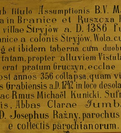 Zdjęcie nr 54: Polichromia ścian kościoła odpowiada podziałom architektonicznym wnętrza wydzielonym przez pilastry. Malowany zielony cokół w jednej czwartej wysokości ścian wyodrębniony jest pasem ornamentu geometrycznego, w nawie w jego polu znajdują się żółte prostokąty z dekoracją geometryczną, w prezbiterium malowana jasnozielona tkanina z dwoma pasami ornamentu roślinnego, medalionami z monogramami Marii i koronami oraz z motywem lilii heraldycznych i rozet. Trzony pilastrów wnętrza bladożółte z malowanymi płycinami dekorowanymi kampanulami, głowice zdobione malowanym kimationem. Na osi pilastrów, w partii fryzu, na tle niebieskich prostokątów uskrzydlone główki anielskie, pomiędzy nimi fryz wypełniony różowo-pomarańczowymi malowanymi płycinami w błękitnym obramieniu o fantazyjnym wykroju, dekorowanymi kampanulami. Belkowanie zamknięte malowanym pasem ornamentu geometrycznego. W polach pomiędzy pilastrami malowane płyciny o fantazyjnym kształcie zbliżonym do prostokąta, ujęte ramą zakończoną kartuszem, ich pola wypełnione są dekoracją geometryczną składającą się z krzyży równoramiennych w glorii i rozet wykonanych techniką patronową. Otwory okienne ujęte są malowanymi, imitującymi profilowanie obramieniami, otwory drzwiowe iluzjonistycznymi portalami z uszakami: portal w nawie zwieńczony jest kartuszem, a portal w prezbiterium zwieńczony jest szczytem zamkniętym fragmentem gzymsu w formie łuku segmentowego nadwieszonego podtrzymywanym przez spływy wolutowe. Pod chórem muzycznym malowane tablice pamiątkowe ujęte ramą, na ścianie północnej z napisem: „Ecclam hanc sub titulo Assumptionis B.V. Mariae a strenuo / milite Wierzbięta in Branice et Ruszcza Haerede pimo in / Wola juxta fines villae Stryjów a D. 1386 fundatam decimis / ex praedio Branice a colonis Stryjów, Wola, cuius sors est Grabie / Szczurów Zymbrzeg et ibidem taberna cum duobus pratis ac lacubus / Orzek et Piotrek ditatam, proper alluviem Vistulae  curatus suus / in hunc locum, qui erat pratum Gruczyn, ecclae dotale transtulit, / Hac tandem post annos 356 collapsa, quam vides, A.R.D. Jacobus Cichoński, parochus Grabiensis a.D. 1742 in loco desolatae  novam erexit. / Consecravit Illmus ac Rmus Michaël Kunicki, Sufraganeus Eppus. / Cracoviensis, Abbas Clarae Tumbae a D. 1749. / Restauravit A.R.D. Josephus Raźny, parochus Grabiensis a.D. 1907. / e colectis parochianorum.”; na ścianie południowej z napisem: „Ku Pamięci! / Dzieci Moje Najmilsze - Ja Prastara Świątynia / Polska dziękuję Wam za serdeczną troskę / o mnie. Oto dzięki Waszym ofiarom Drodzy / Rodzice i Twoim wysiłkom Kochana Młodzieży / w r. 1959 odnowiło się moje oblicze - rozjaśniały /  moje ołtarze, a w r. 1960 zabrzmiał mój nowy / organ na większą chwałę Bożą. Ja Was za to / rodzę na nowo do życia łaski. Ja Was błogosławię / na życie rodzinne. Ja Was prowadzę ku Bogu. Ja / Was także żegnam poraz ostatni, gdy przechodzicie / z tego padołu płaczu do wieczności, aby / Was znowu powitać kiedyś w niebie.”. Na ścianie zachodniej, pod chórem, nad środkowym otworem przejściowym pozostałości dawnego iluzjonistycznego portalu z kartuszem herbowym. Na stropie prezbiterium wydzielone pole o kształcie powtarzającym plan prezbiterium, wewnątrz pole w formie kwadratu o wklęsłych narożach z wpisanym polem o fantazyjnym zarysie zbliżonym do owalu ze sceną Wniebowzięcia Najświętszej Marii Panny. W narożach owalne pola z czterema istotami apokaliptycznymi. Prosta belka tęczowa w kolorze zielonym, o profilowaniach w kolorze niebieskim i różowym, z napisem: „JEZU ZMIŁUJ SIĘ NAD NAMI”. Na stropie nawy prostokątne pole wydzielone grubym bladoróżowym obramieniem z płycinami o nieregularnym kształcie wypełnionymi kratką regencyjną i rozetami alternowanymi medalionami z rozetami, naroża dekorowane są wstęgą regencyjną i akantem. Wewnątrz pole o fantazyjnym wykroju zbliżonym do owalu ze sceną Koronacji Najświętszej Marii Panny, flankowane przez dwie malowane błękitne płyciny o nieregularnym kształcie wypełnione rozetkami. W narożach, w ozdobnych kartuszach herby Pogoni Litewskiej i Orła Białego.
