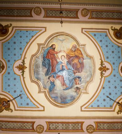 Zdjęcie nr 18: Polichromia ścian kościoła odpowiada podziałom architektonicznym wnętrza wydzielonym przez pilastry. Malowany zielony cokół w jednej czwartej wysokości ścian wyodrębniony jest pasem ornamentu geometrycznego, w nawie w jego polu znajdują się żółte prostokąty z dekoracją geometryczną, w prezbiterium malowana jasnozielona tkanina z dwoma pasami ornamentu roślinnego, medalionami z monogramami Marii i koronami oraz z motywem lilii heraldycznych i rozet. Trzony pilastrów wnętrza bladożółte z malowanymi płycinami dekorowanymi kampanulami, głowice zdobione malowanym kimationem. Na osi pilastrów, w partii fryzu, na tle niebieskich prostokątów uskrzydlone główki anielskie, pomiędzy nimi fryz wypełniony różowo-pomarańczowymi malowanymi płycinami w błękitnym obramieniu o fantazyjnym wykroju, dekorowanymi kampanulami. Belkowanie zamknięte malowanym pasem ornamentu geometrycznego. W polach pomiędzy pilastrami malowane płyciny o fantazyjnym kształcie zbliżonym do prostokąta, ujęte ramą zakończoną kartuszem, ich pola wypełnione są dekoracją geometryczną składającą się z krzyży równoramiennych w glorii i rozet wykonanych techniką patronową. Otwory okienne ujęte są malowanymi, imitującymi profilowanie obramieniami, otwory drzwiowe iluzjonistycznymi portalami z uszakami: portal w nawie zwieńczony jest kartuszem, a portal w prezbiterium zwieńczony jest szczytem zamkniętym fragmentem gzymsu w formie łuku segmentowego nadwieszonego podtrzymywanym przez spływy wolutowe. Pod chórem muzycznym malowane tablice pamiątkowe ujęte ramą, na ścianie północnej z napisem: „Ecclam hanc sub titulo Assumptionis B.V. Mariae a strenuo / milite Wierzbięta in Branice et Ruszcza Haerede pimo in / Wola juxta fines villae Stryjów a D. 1386 fundatam decimis / ex praedio Branice a colonis Stryjów, Wola, cuius sors est Grabie / Szczurów Zymbrzeg et ibidem taberna cum duobus pratis ac lacubus / Orzek et Piotrek ditatam, proper alluviem Vistulae  curatus suus / in hunc locum, qui erat pratum Gruczyn, ecclae dotale transtulit, / Hac tandem post annos 356 collapsa, quam vides, A.R.D. Jacobus Cichoński, parochus Grabiensis a.D. 1742 in loco desolatae  novam erexit. / Consecravit Illmus ac Rmus Michaël Kunicki, Sufraganeus Eppus. / Cracoviensis, Abbas Clarae Tumbae a D. 1749. / Restauravit A.R.D. Josephus Raźny, parochus Grabiensis a.D. 1907. / e colectis parochianorum.”; na ścianie południowej z napisem: „Ku Pamięci! / Dzieci Moje Najmilsze - Ja Prastara Świątynia / Polska dziękuję Wam za serdeczną troskę / o mnie. Oto dzięki Waszym ofiarom Drodzy / Rodzice i Twoim wysiłkom Kochana Młodzieży / w r. 1959 odnowiło się moje oblicze - rozjaśniały /  moje ołtarze, a w r. 1960 zabrzmiał mój nowy / organ na większą chwałę Bożą. Ja Was za to / rodzę na nowo do życia łaski. Ja Was błogosławię / na życie rodzinne. Ja Was prowadzę ku Bogu. Ja / Was także żegnam poraz ostatni, gdy przechodzicie / z tego padołu płaczu do wieczności, aby / Was znowu powitać kiedyś w niebie.”. Na ścianie zachodniej, pod chórem, nad środkowym otworem przejściowym pozostałości dawnego iluzjonistycznego portalu z kartuszem herbowym. Na stropie prezbiterium wydzielone pole o kształcie powtarzającym plan prezbiterium, wewnątrz pole w formie kwadratu o wklęsłych narożach z wpisanym polem o fantazyjnym zarysie zbliżonym do owalu ze sceną Wniebowzięcia Najświętszej Marii Panny. W narożach owalne pola z czterema istotami apokaliptycznymi. Prosta belka tęczowa w kolorze zielonym, o profilowaniach w kolorze niebieskim i różowym, z napisem: „JEZU ZMIŁUJ SIĘ NAD NAMI”. Na stropie nawy prostokątne pole wydzielone grubym bladoróżowym obramieniem z płycinami o nieregularnym kształcie wypełnionymi kratką regencyjną i rozetami alternowanymi medalionami z rozetami, naroża dekorowane są wstęgą regencyjną i akantem. Wewnątrz pole o fantazyjnym wykroju zbliżonym do owalu ze sceną Koronacji Najświętszej Marii Panny, flankowane przez dwie malowane błękitne płyciny o nieregularnym kształcie wypełnione rozetkami. W narożach, w ozdobnych kartuszach herby Pogoni Litewskiej i Orła Białego.
