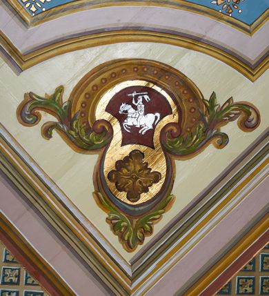 Zdjęcie nr 22: Polichromia ścian kościoła odpowiada podziałom architektonicznym wnętrza wydzielonym przez pilastry. Malowany zielony cokół w jednej czwartej wysokości ścian wyodrębniony jest pasem ornamentu geometrycznego, w nawie w jego polu znajdują się żółte prostokąty z dekoracją geometryczną, w prezbiterium malowana jasnozielona tkanina z dwoma pasami ornamentu roślinnego, medalionami z monogramami Marii i koronami oraz z motywem lilii heraldycznych i rozet. Trzony pilastrów wnętrza bladożółte z malowanymi płycinami dekorowanymi kampanulami, głowice zdobione malowanym kimationem. Na osi pilastrów, w partii fryzu, na tle niebieskich prostokątów uskrzydlone główki anielskie, pomiędzy nimi fryz wypełniony różowo-pomarańczowymi malowanymi płycinami w błękitnym obramieniu o fantazyjnym wykroju, dekorowanymi kampanulami. Belkowanie zamknięte malowanym pasem ornamentu geometrycznego. W polach pomiędzy pilastrami malowane płyciny o fantazyjnym kształcie zbliżonym do prostokąta, ujęte ramą zakończoną kartuszem, ich pola wypełnione są dekoracją geometryczną składającą się z krzyży równoramiennych w glorii i rozet wykonanych techniką patronową. Otwory okienne ujęte są malowanymi, imitującymi profilowanie obramieniami, otwory drzwiowe iluzjonistycznymi portalami z uszakami: portal w nawie zwieńczony jest kartuszem, a portal w prezbiterium zwieńczony jest szczytem zamkniętym fragmentem gzymsu w formie łuku segmentowego nadwieszonego podtrzymywanym przez spływy wolutowe. Pod chórem muzycznym malowane tablice pamiątkowe ujęte ramą, na ścianie północnej z napisem: „Ecclam hanc sub titulo Assumptionis B.V. Mariae a strenuo / milite Wierzbięta in Branice et Ruszcza Haerede pimo in / Wola juxta fines villae Stryjów a D. 1386 fundatam decimis / ex praedio Branice a colonis Stryjów, Wola, cuius sors est Grabie / Szczurów Zymbrzeg et ibidem taberna cum duobus pratis ac lacubus / Orzek et Piotrek ditatam, proper alluviem Vistulae  curatus suus / in hunc locum, qui erat pratum Gruczyn, ecclae dotale transtulit, / Hac tandem post annos 356 collapsa, quam vides, A.R.D. Jacobus Cichoński, parochus Grabiensis a.D. 1742 in loco desolatae  novam erexit. / Consecravit Illmus ac Rmus Michaël Kunicki, Sufraganeus Eppus. / Cracoviensis, Abbas Clarae Tumbae a D. 1749. / Restauravit A.R.D. Josephus Raźny, parochus Grabiensis a.D. 1907. / e colectis parochianorum.”; na ścianie południowej z napisem: „Ku Pamięci! / Dzieci Moje Najmilsze - Ja Prastara Świątynia / Polska dziękuję Wam za serdeczną troskę / o mnie. Oto dzięki Waszym ofiarom Drodzy / Rodzice i Twoim wysiłkom Kochana Młodzieży / w r. 1959 odnowiło się moje oblicze - rozjaśniały /  moje ołtarze, a w r. 1960 zabrzmiał mój nowy / organ na większą chwałę Bożą. Ja Was za to / rodzę na nowo do życia łaski. Ja Was błogosławię / na życie rodzinne. Ja Was prowadzę ku Bogu. Ja / Was także żegnam poraz ostatni, gdy przechodzicie / z tego padołu płaczu do wieczności, aby / Was znowu powitać kiedyś w niebie.”. Na ścianie zachodniej, pod chórem, nad środkowym otworem przejściowym pozostałości dawnego iluzjonistycznego portalu z kartuszem herbowym. Na stropie prezbiterium wydzielone pole o kształcie powtarzającym plan prezbiterium, wewnątrz pole w formie kwadratu o wklęsłych narożach z wpisanym polem o fantazyjnym zarysie zbliżonym do owalu ze sceną Wniebowzięcia Najświętszej Marii Panny. W narożach owalne pola z czterema istotami apokaliptycznymi. Prosta belka tęczowa w kolorze zielonym, o profilowaniach w kolorze niebieskim i różowym, z napisem: „JEZU ZMIŁUJ SIĘ NAD NAMI”. Na stropie nawy prostokątne pole wydzielone grubym bladoróżowym obramieniem z płycinami o nieregularnym kształcie wypełnionymi kratką regencyjną i rozetami alternowanymi medalionami z rozetami, naroża dekorowane są wstęgą regencyjną i akantem. Wewnątrz pole o fantazyjnym wykroju zbliżonym do owalu ze sceną Koronacji Najświętszej Marii Panny, flankowane przez dwie malowane błękitne płyciny o nieregularnym kształcie wypełnione rozetkami. W narożach, w ozdobnych kartuszach herby Pogoni Litewskiej i Orła Białego.
