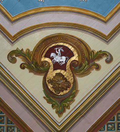 Zdjęcie nr 21: Polichromia ścian kościoła odpowiada podziałom architektonicznym wnętrza wydzielonym przez pilastry. Malowany zielony cokół w jednej czwartej wysokości ścian wyodrębniony jest pasem ornamentu geometrycznego, w nawie w jego polu znajdują się żółte prostokąty z dekoracją geometryczną, w prezbiterium malowana jasnozielona tkanina z dwoma pasami ornamentu roślinnego, medalionami z monogramami Marii i koronami oraz z motywem lilii heraldycznych i rozet. Trzony pilastrów wnętrza bladożółte z malowanymi płycinami dekorowanymi kampanulami, głowice zdobione malowanym kimationem. Na osi pilastrów, w partii fryzu, na tle niebieskich prostokątów uskrzydlone główki anielskie, pomiędzy nimi fryz wypełniony różowo-pomarańczowymi malowanymi płycinami w błękitnym obramieniu o fantazyjnym wykroju, dekorowanymi kampanulami. Belkowanie zamknięte malowanym pasem ornamentu geometrycznego. W polach pomiędzy pilastrami malowane płyciny o fantazyjnym kształcie zbliżonym do prostokąta, ujęte ramą zakończoną kartuszem, ich pola wypełnione są dekoracją geometryczną składającą się z krzyży równoramiennych w glorii i rozet wykonanych techniką patronową. Otwory okienne ujęte są malowanymi, imitującymi profilowanie obramieniami, otwory drzwiowe iluzjonistycznymi portalami z uszakami: portal w nawie zwieńczony jest kartuszem, a portal w prezbiterium zwieńczony jest szczytem zamkniętym fragmentem gzymsu w formie łuku segmentowego nadwieszonego podtrzymywanym przez spływy wolutowe. Pod chórem muzycznym malowane tablice pamiątkowe ujęte ramą, na ścianie północnej z napisem: „Ecclam hanc sub titulo Assumptionis B.V. Mariae a strenuo / milite Wierzbięta in Branice et Ruszcza Haerede pimo in / Wola juxta fines villae Stryjów a D. 1386 fundatam decimis / ex praedio Branice a colonis Stryjów, Wola, cuius sors est Grabie / Szczurów Zymbrzeg et ibidem taberna cum duobus pratis ac lacubus / Orzek et Piotrek ditatam, proper alluviem Vistulae  curatus suus / in hunc locum, qui erat pratum Gruczyn, ecclae dotale transtulit, / Hac tandem post annos 356 collapsa, quam vides, A.R.D. Jacobus Cichoński, parochus Grabiensis a.D. 1742 in loco desolatae  novam erexit. / Consecravit Illmus ac Rmus Michaël Kunicki, Sufraganeus Eppus. / Cracoviensis, Abbas Clarae Tumbae a D. 1749. / Restauravit A.R.D. Josephus Raźny, parochus Grabiensis a.D. 1907. / e colectis parochianorum.”; na ścianie południowej z napisem: „Ku Pamięci! / Dzieci Moje Najmilsze - Ja Prastara Świątynia / Polska dziękuję Wam za serdeczną troskę / o mnie. Oto dzięki Waszym ofiarom Drodzy / Rodzice i Twoim wysiłkom Kochana Młodzieży / w r. 1959 odnowiło się moje oblicze - rozjaśniały /  moje ołtarze, a w r. 1960 zabrzmiał mój nowy / organ na większą chwałę Bożą. Ja Was za to / rodzę na nowo do życia łaski. Ja Was błogosławię / na życie rodzinne. Ja Was prowadzę ku Bogu. Ja / Was także żegnam poraz ostatni, gdy przechodzicie / z tego padołu płaczu do wieczności, aby / Was znowu powitać kiedyś w niebie.”. Na ścianie zachodniej, pod chórem, nad środkowym otworem przejściowym pozostałości dawnego iluzjonistycznego portalu z kartuszem herbowym. Na stropie prezbiterium wydzielone pole o kształcie powtarzającym plan prezbiterium, wewnątrz pole w formie kwadratu o wklęsłych narożach z wpisanym polem o fantazyjnym zarysie zbliżonym do owalu ze sceną Wniebowzięcia Najświętszej Marii Panny. W narożach owalne pola z czterema istotami apokaliptycznymi. Prosta belka tęczowa w kolorze zielonym, o profilowaniach w kolorze niebieskim i różowym, z napisem: „JEZU ZMIŁUJ SIĘ NAD NAMI”. Na stropie nawy prostokątne pole wydzielone grubym bladoróżowym obramieniem z płycinami o nieregularnym kształcie wypełnionymi kratką regencyjną i rozetami alternowanymi medalionami z rozetami, naroża dekorowane są wstęgą regencyjną i akantem. Wewnątrz pole o fantazyjnym wykroju zbliżonym do owalu ze sceną Koronacji Najświętszej Marii Panny, flankowane przez dwie malowane błękitne płyciny o nieregularnym kształcie wypełnione rozetkami. W narożach, w ozdobnych kartuszach herby Pogoni Litewskiej i Orła Białego.
