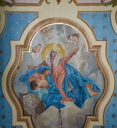 Zdjęcie nr 38: Polichromia ścian kościoła odpowiada podziałom architektonicznym wnętrza wydzielonym przez pilastry. Malowany zielony cokół w jednej czwartej wysokości ścian wyodrębniony jest pasem ornamentu geometrycznego, w nawie w jego polu znajdują się żółte prostokąty z dekoracją geometryczną, w prezbiterium malowana jasnozielona tkanina z dwoma pasami ornamentu roślinnego, medalionami z monogramami Marii i koronami oraz z motywem lilii heraldycznych i rozet. Trzony pilastrów wnętrza bladożółte z malowanymi płycinami dekorowanymi kampanulami, głowice zdobione malowanym kimationem. Na osi pilastrów, w partii fryzu, na tle niebieskich prostokątów uskrzydlone główki anielskie, pomiędzy nimi fryz wypełniony różowo-pomarańczowymi malowanymi płycinami w błękitnym obramieniu o fantazyjnym wykroju, dekorowanymi kampanulami. Belkowanie zamknięte malowanym pasem ornamentu geometrycznego. W polach pomiędzy pilastrami malowane płyciny o fantazyjnym kształcie zbliżonym do prostokąta, ujęte ramą zakończoną kartuszem, ich pola wypełnione są dekoracją geometryczną składającą się z krzyży równoramiennych w glorii i rozet wykonanych techniką patronową. Otwory okienne ujęte są malowanymi, imitującymi profilowanie obramieniami, otwory drzwiowe iluzjonistycznymi portalami z uszakami: portal w nawie zwieńczony jest kartuszem, a portal w prezbiterium zwieńczony jest szczytem zamkniętym fragmentem gzymsu w formie łuku segmentowego nadwieszonego podtrzymywanym przez spływy wolutowe. Pod chórem muzycznym malowane tablice pamiątkowe ujęte ramą, na ścianie północnej z napisem: „Ecclam hanc sub titulo Assumptionis B.V. Mariae a strenuo / milite Wierzbięta in Branice et Ruszcza Haerede pimo in / Wola juxta fines villae Stryjów a D. 1386 fundatam decimis / ex praedio Branice a colonis Stryjów, Wola, cuius sors est Grabie / Szczurów Zymbrzeg et ibidem taberna cum duobus pratis ac lacubus / Orzek et Piotrek ditatam, proper alluviem Vistulae  curatus suus / in hunc locum, qui erat pratum Gruczyn, ecclae dotale transtulit, / Hac tandem post annos 356 collapsa, quam vides, A.R.D. Jacobus Cichoński, parochus Grabiensis a.D. 1742 in loco desolatae  novam erexit. / Consecravit Illmus ac Rmus Michaël Kunicki, Sufraganeus Eppus. / Cracoviensis, Abbas Clarae Tumbae a D. 1749. / Restauravit A.R.D. Josephus Raźny, parochus Grabiensis a.D. 1907. / e colectis parochianorum.”; na ścianie południowej z napisem: „Ku Pamięci! / Dzieci Moje Najmilsze - Ja Prastara Świątynia / Polska dziękuję Wam za serdeczną troskę / o mnie. Oto dzięki Waszym ofiarom Drodzy / Rodzice i Twoim wysiłkom Kochana Młodzieży / w r. 1959 odnowiło się moje oblicze - rozjaśniały /  moje ołtarze, a w r. 1960 zabrzmiał mój nowy / organ na większą chwałę Bożą. Ja Was za to / rodzę na nowo do życia łaski. Ja Was błogosławię / na życie rodzinne. Ja Was prowadzę ku Bogu. Ja / Was także żegnam poraz ostatni, gdy przechodzicie / z tego padołu płaczu do wieczności, aby / Was znowu powitać kiedyś w niebie.”. Na ścianie zachodniej, pod chórem, nad środkowym otworem przejściowym pozostałości dawnego iluzjonistycznego portalu z kartuszem herbowym. Na stropie prezbiterium wydzielone pole o kształcie powtarzającym plan prezbiterium, wewnątrz pole w formie kwadratu o wklęsłych narożach z wpisanym polem o fantazyjnym zarysie zbliżonym do owalu ze sceną Wniebowzięcia Najświętszej Marii Panny. W narożach owalne pola z czterema istotami apokaliptycznymi. Prosta belka tęczowa w kolorze zielonym, o profilowaniach w kolorze niebieskim i różowym, z napisem: „JEZU ZMIŁUJ SIĘ NAD NAMI”. Na stropie nawy prostokątne pole wydzielone grubym bladoróżowym obramieniem z płycinami o nieregularnym kształcie wypełnionymi kratką regencyjną i rozetami alternowanymi medalionami z rozetami, naroża dekorowane są wstęgą regencyjną i akantem. Wewnątrz pole o fantazyjnym wykroju zbliżonym do owalu ze sceną Koronacji Najświętszej Marii Panny, flankowane przez dwie malowane błękitne płyciny o nieregularnym kształcie wypełnione rozetkami. W narożach, w ozdobnych kartuszach herby Pogoni Litewskiej i Orła Białego.
