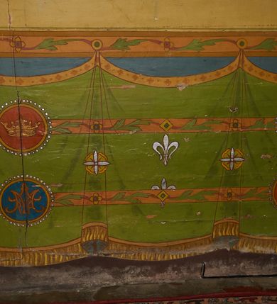 Zdjęcie nr 5: Polichromia ścian kościoła odpowiada podziałom architektonicznym wnętrza wydzielonym przez pilastry. Malowany zielony cokół w jednej czwartej wysokości ścian wyodrębniony jest pasem ornamentu geometrycznego, w nawie w jego polu znajdują się żółte prostokąty z dekoracją geometryczną, w prezbiterium malowana jasnozielona tkanina z dwoma pasami ornamentu roślinnego, medalionami z monogramami Marii i koronami oraz z motywem lilii heraldycznych i rozet. Trzony pilastrów wnętrza bladożółte z malowanymi płycinami dekorowanymi kampanulami, głowice zdobione malowanym kimationem. Na osi pilastrów, w partii fryzu, na tle niebieskich prostokątów uskrzydlone główki anielskie, pomiędzy nimi fryz wypełniony różowo-pomarańczowymi malowanymi płycinami w błękitnym obramieniu o fantazyjnym wykroju, dekorowanymi kampanulami. Belkowanie zamknięte malowanym pasem ornamentu geometrycznego. W polach pomiędzy pilastrami malowane płyciny o fantazyjnym kształcie zbliżonym do prostokąta, ujęte ramą zakończoną kartuszem, ich pola wypełnione są dekoracją geometryczną składającą się z krzyży równoramiennych w glorii i rozet wykonanych techniką patronową. Otwory okienne ujęte są malowanymi, imitującymi profilowanie obramieniami, otwory drzwiowe iluzjonistycznymi portalami z uszakami: portal w nawie zwieńczony jest kartuszem, a portal w prezbiterium zwieńczony jest szczytem zamkniętym fragmentem gzymsu w formie łuku segmentowego nadwieszonego podtrzymywanym przez spływy wolutowe. Pod chórem muzycznym malowane tablice pamiątkowe ujęte ramą, na ścianie północnej z napisem: „Ecclam hanc sub titulo Assumptionis B.V. Mariae a strenuo / milite Wierzbięta in Branice et Ruszcza Haerede pimo in / Wola juxta fines villae Stryjów a D. 1386 fundatam decimis / ex praedio Branice a colonis Stryjów, Wola, cuius sors est Grabie / Szczurów Zymbrzeg et ibidem taberna cum duobus pratis ac lacubus / Orzek et Piotrek ditatam, proper alluviem Vistulae  curatus suus / in hunc locum, qui erat pratum Gruczyn, ecclae dotale transtulit, / Hac tandem post annos 356 collapsa, quam vides, A.R.D. Jacobus Cichoński, parochus Grabiensis a.D. 1742 in loco desolatae  novam erexit. / Consecravit Illmus ac Rmus Michaël Kunicki, Sufraganeus Eppus. / Cracoviensis, Abbas Clarae Tumbae a D. 1749. / Restauravit A.R.D. Josephus Raźny, parochus Grabiensis a.D. 1907. / e colectis parochianorum.”; na ścianie południowej z napisem: „Ku Pamięci! / Dzieci Moje Najmilsze - Ja Prastara Świątynia / Polska dziękuję Wam za serdeczną troskę / o mnie. Oto dzięki Waszym ofiarom Drodzy / Rodzice i Twoim wysiłkom Kochana Młodzieży / w r. 1959 odnowiło się moje oblicze - rozjaśniały /  moje ołtarze, a w r. 1960 zabrzmiał mój nowy / organ na większą chwałę Bożą. Ja Was za to / rodzę na nowo do życia łaski. Ja Was błogosławię / na życie rodzinne. Ja Was prowadzę ku Bogu. Ja / Was także żegnam poraz ostatni, gdy przechodzicie / z tego padołu płaczu do wieczności, aby / Was znowu powitać kiedyś w niebie.”. Na ścianie zachodniej, pod chórem, nad środkowym otworem przejściowym pozostałości dawnego iluzjonistycznego portalu z kartuszem herbowym. Na stropie prezbiterium wydzielone pole o kształcie powtarzającym plan prezbiterium, wewnątrz pole w formie kwadratu o wklęsłych narożach z wpisanym polem o fantazyjnym zarysie zbliżonym do owalu ze sceną Wniebowzięcia Najświętszej Marii Panny. W narożach owalne pola z czterema istotami apokaliptycznymi. Prosta belka tęczowa w kolorze zielonym, o profilowaniach w kolorze niebieskim i różowym, z napisem: „JEZU ZMIŁUJ SIĘ NAD NAMI”. Na stropie nawy prostokątne pole wydzielone grubym bladoróżowym obramieniem z płycinami o nieregularnym kształcie wypełnionymi kratką regencyjną i rozetami alternowanymi medalionami z rozetami, naroża dekorowane są wstęgą regencyjną i akantem. Wewnątrz pole o fantazyjnym wykroju zbliżonym do owalu ze sceną Koronacji Najświętszej Marii Panny, flankowane przez dwie malowane błękitne płyciny o nieregularnym kształcie wypełnione rozetkami. W narożach, w ozdobnych kartuszach herby Pogoni Litewskiej i Orła Białego.
