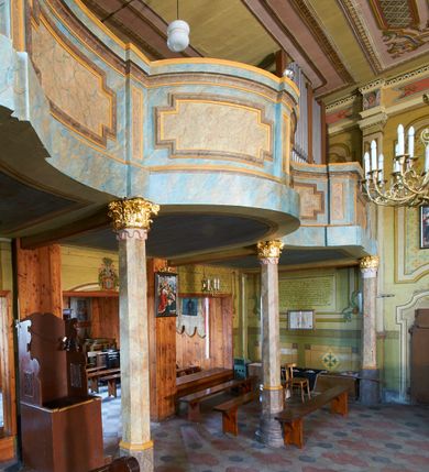 Zdjęcie nr 41: Polichromia ścian kościoła odpowiada podziałom architektonicznym wnętrza wydzielonym przez pilastry. Malowany zielony cokół w jednej czwartej wysokości ścian wyodrębniony jest pasem ornamentu geometrycznego, w nawie w jego polu znajdują się żółte prostokąty z dekoracją geometryczną, w prezbiterium malowana jasnozielona tkanina z dwoma pasami ornamentu roślinnego, medalionami z monogramami Marii i koronami oraz z motywem lilii heraldycznych i rozet. Trzony pilastrów wnętrza bladożółte z malowanymi płycinami dekorowanymi kampanulami, głowice zdobione malowanym kimationem. Na osi pilastrów, w partii fryzu, na tle niebieskich prostokątów uskrzydlone główki anielskie, pomiędzy nimi fryz wypełniony różowo-pomarańczowymi malowanymi płycinami w błękitnym obramieniu o fantazyjnym wykroju, dekorowanymi kampanulami. Belkowanie zamknięte malowanym pasem ornamentu geometrycznego. W polach pomiędzy pilastrami malowane płyciny o fantazyjnym kształcie zbliżonym do prostokąta, ujęte ramą zakończoną kartuszem, ich pola wypełnione są dekoracją geometryczną składającą się z krzyży równoramiennych w glorii i rozet wykonanych techniką patronową. Otwory okienne ujęte są malowanymi, imitującymi profilowanie obramieniami, otwory drzwiowe iluzjonistycznymi portalami z uszakami: portal w nawie zwieńczony jest kartuszem, a portal w prezbiterium zwieńczony jest szczytem zamkniętym fragmentem gzymsu w formie łuku segmentowego nadwieszonego podtrzymywanym przez spływy wolutowe. Pod chórem muzycznym malowane tablice pamiątkowe ujęte ramą, na ścianie północnej z napisem: „Ecclam hanc sub titulo Assumptionis B.V. Mariae a strenuo / milite Wierzbięta in Branice et Ruszcza Haerede pimo in / Wola juxta fines villae Stryjów a D. 1386 fundatam decimis / ex praedio Branice a colonis Stryjów, Wola, cuius sors est Grabie / Szczurów Zymbrzeg et ibidem taberna cum duobus pratis ac lacubus / Orzek et Piotrek ditatam, proper alluviem Vistulae  curatus suus / in hunc locum, qui erat pratum Gruczyn, ecclae dotale transtulit, / Hac tandem post annos 356 collapsa, quam vides, A.R.D. Jacobus Cichoński, parochus Grabiensis a.D. 1742 in loco desolatae  novam erexit. / Consecravit Illmus ac Rmus Michaël Kunicki, Sufraganeus Eppus. / Cracoviensis, Abbas Clarae Tumbae a D. 1749. / Restauravit A.R.D. Josephus Raźny, parochus Grabiensis a.D. 1907. / e colectis parochianorum.”; na ścianie południowej z napisem: „Ku Pamięci! / Dzieci Moje Najmilsze - Ja Prastara Świątynia / Polska dziękuję Wam za serdeczną troskę / o mnie. Oto dzięki Waszym ofiarom Drodzy / Rodzice i Twoim wysiłkom Kochana Młodzieży / w r. 1959 odnowiło się moje oblicze - rozjaśniały /  moje ołtarze, a w r. 1960 zabrzmiał mój nowy / organ na większą chwałę Bożą. Ja Was za to / rodzę na nowo do życia łaski. Ja Was błogosławię / na życie rodzinne. Ja Was prowadzę ku Bogu. Ja / Was także żegnam poraz ostatni, gdy przechodzicie / z tego padołu płaczu do wieczności, aby / Was znowu powitać kiedyś w niebie.”. Na ścianie zachodniej, pod chórem, nad środkowym otworem przejściowym pozostałości dawnego iluzjonistycznego portalu z kartuszem herbowym. Na stropie prezbiterium wydzielone pole o kształcie powtarzającym plan prezbiterium, wewnątrz pole w formie kwadratu o wklęsłych narożach z wpisanym polem o fantazyjnym zarysie zbliżonym do owalu ze sceną Wniebowzięcia Najświętszej Marii Panny. W narożach owalne pola z czterema istotami apokaliptycznymi. Prosta belka tęczowa w kolorze zielonym, o profilowaniach w kolorze niebieskim i różowym, z napisem: „JEZU ZMIŁUJ SIĘ NAD NAMI”. Na stropie nawy prostokątne pole wydzielone grubym bladoróżowym obramieniem z płycinami o nieregularnym kształcie wypełnionymi kratką regencyjną i rozetami alternowanymi medalionami z rozetami, naroża dekorowane są wstęgą regencyjną i akantem. Wewnątrz pole o fantazyjnym wykroju zbliżonym do owalu ze sceną Koronacji Najświętszej Marii Panny, flankowane przez dwie malowane błękitne płyciny o nieregularnym kształcie wypełnione rozetkami. W narożach, w ozdobnych kartuszach herby Pogoni Litewskiej i Orła Białego.
