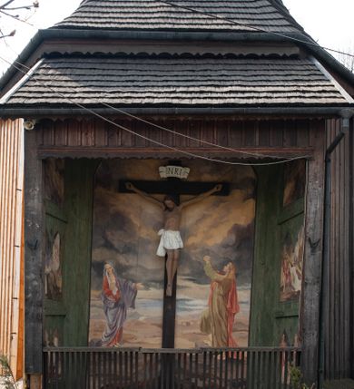 Zdjęcie nr 4: Figura Chrystusa umarłego, przybita jest do prostego krzyża trzema gwoździami. Ukazana została w lekkim zwisie ciała, o szeroko rozpostartych ramionach z zaciśniętymi dłońmi, nogi są delikatnie ugięte w kolanach, a stopy w układzie prawa na lewą. Twarz pociągła o wyraźnych rysach łuków brwiowych i prostego nosa, oczy są zamknięte. Okolona jest brodą oraz włosami opadającymi na ramiona. Ciało jest wychudzone, o delikatnym modelunku klatki piersiowej, z podkreślonymi mięśniami ramion wyłamanych z barków. Białe perizonium sięgające połowy ud, zawiązane jest na prawym biodrze ze zwisem tkaniny. Polichromia ciała naturalistyczna z delikatnie zaznaczonymi krwawiącymi ranami. 