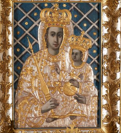 Zdjęcie nr 11: Ołtarz prostopadłościenny, murowany, w drewnianej obudowie, z drewnianą mensą. Antependium w kształcie leżącego prostokąta ujętego profilowaną ramą, dekorowane monogramem imienia MARIA w środku pola i symetrycznie rozłożonymi po bokach różanymi gałązkami. Na mensie ustawione architektoniczne tabernakulum. 
Nastawa w formie paludamentu podwiązanego po bokach sznurem z chwostami, lamowanego frędzlą, zwieńczonego baldachimem utworzonym z fragmentu wklęsło-wypukłego gzymsu z lambrekinem i rokokowym kartuszem. W polu paludamentu wnęka w kształcie stojącego prostokąta o wklęsłych górnych narożach w profilowanej ramie, ustawiona na cokole ujętym spływami wolutowymi. Wewnątrz obraz Matki Boskiej z Dzieciątkiem ujęty grubą ramą dekorowaną akantem i palmetami, ponad nim uskrzydlona główka anielska. Wnękę flankują dwa unoszące się putta, powyżej niej kartusz z monogramem Marii. Paludament dekorowany plastycznymi gwiazdami. Po bokach nastawy dwie bramki z otworami wejściowymi w formie stojącego prostokąta, zamkniętymi prostym gzymsem ze znajdującymi się powyżej postumentami dekorowanymi różami, na których stoją dwie figury aniołów. W górnej części, z obydwu stron nastawy poziome listwy konstrukcyjne mocujące całość retabulum do ścian bocznych prezbiterium, dekorowane są uskrzydlonymi główkami anielskimi z muszlami oraz roślinnymi festonami. Paludament polichromowany wewnątrz na biało, zewnątrz na niebiesko z pozłacanymi detalami.

