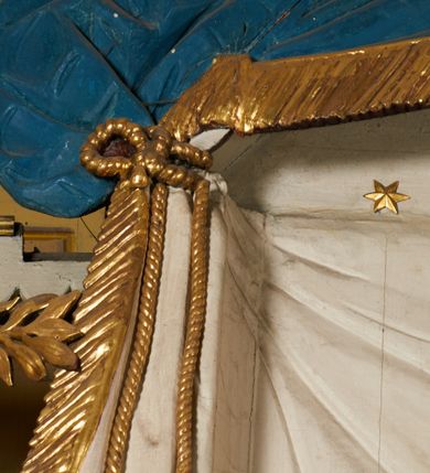 Zdjęcie nr 33: Ołtarz prostopadłościenny, murowany, w drewnianej obudowie, z drewnianą mensą. Antependium w kształcie leżącego prostokąta ujętego profilowaną ramą, dekorowane monogramem imienia MARIA w środku pola i symetrycznie rozłożonymi po bokach różanymi gałązkami. Na mensie ustawione architektoniczne tabernakulum. 
Nastawa w formie paludamentu podwiązanego po bokach sznurem z chwostami, lamowanego frędzlą, zwieńczonego baldachimem utworzonym z fragmentu wklęsło-wypukłego gzymsu z lambrekinem i rokokowym kartuszem. W polu paludamentu wnęka w kształcie stojącego prostokąta o wklęsłych górnych narożach w profilowanej ramie, ustawiona na cokole ujętym spływami wolutowymi. Wewnątrz obraz Matki Boskiej z Dzieciątkiem ujęty grubą ramą dekorowaną akantem i palmetami, ponad nim uskrzydlona główka anielska. Wnękę flankują dwa unoszące się putta, powyżej niej kartusz z monogramem Marii. Paludament dekorowany plastycznymi gwiazdami. Po bokach nastawy dwie bramki z otworami wejściowymi w formie stojącego prostokąta, zamkniętymi prostym gzymsem ze znajdującymi się powyżej postumentami dekorowanymi różami, na których stoją dwie figury aniołów. W górnej części, z obydwu stron nastawy poziome listwy konstrukcyjne mocujące całość retabulum do ścian bocznych prezbiterium, dekorowane są uskrzydlonymi główkami anielskimi z muszlami oraz roślinnymi festonami. Paludament polichromowany wewnątrz na biało, zewnątrz na niebiesko z pozłacanymi detalami.

