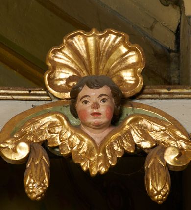 Zdjęcie nr 30: Ołtarz prostopadłościenny, murowany, w drewnianej obudowie, z drewnianą mensą. Antependium w kształcie leżącego prostokąta ujętego profilowaną ramą, dekorowane monogramem imienia MARIA w środku pola i symetrycznie rozłożonymi po bokach różanymi gałązkami. Na mensie ustawione architektoniczne tabernakulum. 
Nastawa w formie paludamentu podwiązanego po bokach sznurem z chwostami, lamowanego frędzlą, zwieńczonego baldachimem utworzonym z fragmentu wklęsło-wypukłego gzymsu z lambrekinem i rokokowym kartuszem. W polu paludamentu wnęka w kształcie stojącego prostokąta o wklęsłych górnych narożach w profilowanej ramie, ustawiona na cokole ujętym spływami wolutowymi. Wewnątrz obraz Matki Boskiej z Dzieciątkiem ujęty grubą ramą dekorowaną akantem i palmetami, ponad nim uskrzydlona główka anielska. Wnękę flankują dwa unoszące się putta, powyżej niej kartusz z monogramem Marii. Paludament dekorowany plastycznymi gwiazdami. Po bokach nastawy dwie bramki z otworami wejściowymi w formie stojącego prostokąta, zamkniętymi prostym gzymsem ze znajdującymi się powyżej postumentami dekorowanymi różami, na których stoją dwie figury aniołów. W górnej części, z obydwu stron nastawy poziome listwy konstrukcyjne mocujące całość retabulum do ścian bocznych prezbiterium, dekorowane są uskrzydlonymi główkami anielskimi z muszlami oraz roślinnymi festonami. Paludament polichromowany wewnątrz na biało, zewnątrz na niebiesko z pozłacanymi detalami.

