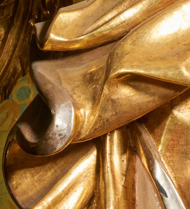 Zdjęcie nr 56: Ołtarz prostopadłościenny, murowany, w drewnianej obudowie, z drewnianą mensą. Antependium w kształcie leżącego prostokąta ujętego profilowaną ramą, dekorowane monogramem imienia MARIA w środku pola i symetrycznie rozłożonymi po bokach różanymi gałązkami. Na mensie ustawione architektoniczne tabernakulum. 
Nastawa w formie paludamentu podwiązanego po bokach sznurem z chwostami, lamowanego frędzlą, zwieńczonego baldachimem utworzonym z fragmentu wklęsło-wypukłego gzymsu z lambrekinem i rokokowym kartuszem. W polu paludamentu wnęka w kształcie stojącego prostokąta o wklęsłych górnych narożach w profilowanej ramie, ustawiona na cokole ujętym spływami wolutowymi. Wewnątrz obraz Matki Boskiej z Dzieciątkiem ujęty grubą ramą dekorowaną akantem i palmetami, ponad nim uskrzydlona główka anielska. Wnękę flankują dwa unoszące się putta, powyżej niej kartusz z monogramem Marii. Paludament dekorowany plastycznymi gwiazdami. Po bokach nastawy dwie bramki z otworami wejściowymi w formie stojącego prostokąta, zamkniętymi prostym gzymsem ze znajdującymi się powyżej postumentami dekorowanymi różami, na których stoją dwie figury aniołów. W górnej części, z obydwu stron nastawy poziome listwy konstrukcyjne mocujące całość retabulum do ścian bocznych prezbiterium, dekorowane są uskrzydlonymi główkami anielskimi z muszlami oraz roślinnymi festonami. Paludament polichromowany wewnątrz na biało, zewnątrz na niebiesko z pozłacanymi detalami.

