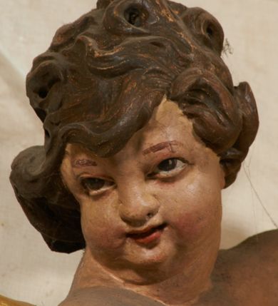 Zdjęcie nr 101: Ołtarz prostopadłościenny, murowany, w drewnianej obudowie, z drewnianą mensą. Antependium w kształcie leżącego prostokąta ujętego profilowaną ramą, dekorowane monogramem imienia MARIA w środku pola i symetrycznie rozłożonymi po bokach różanymi gałązkami. Na mensie ustawione architektoniczne tabernakulum. 
Nastawa w formie paludamentu podwiązanego po bokach sznurem z chwostami, lamowanego frędzlą, zwieńczonego baldachimem utworzonym z fragmentu wklęsło-wypukłego gzymsu z lambrekinem i rokokowym kartuszem. W polu paludamentu wnęka w kształcie stojącego prostokąta o wklęsłych górnych narożach w profilowanej ramie, ustawiona na cokole ujętym spływami wolutowymi. Wewnątrz obraz Matki Boskiej z Dzieciątkiem ujęty grubą ramą dekorowaną akantem i palmetami, ponad nim uskrzydlona główka anielska. Wnękę flankują dwa unoszące się putta, powyżej niej kartusz z monogramem Marii. Paludament dekorowany plastycznymi gwiazdami. Po bokach nastawy dwie bramki z otworami wejściowymi w formie stojącego prostokąta, zamkniętymi prostym gzymsem ze znajdującymi się powyżej postumentami dekorowanymi różami, na których stoją dwie figury aniołów. W górnej części, z obydwu stron nastawy poziome listwy konstrukcyjne mocujące całość retabulum do ścian bocznych prezbiterium, dekorowane są uskrzydlonymi główkami anielskimi z muszlami oraz roślinnymi festonami. Paludament polichromowany wewnątrz na biało, zewnątrz na niebiesko z pozłacanymi detalami.

