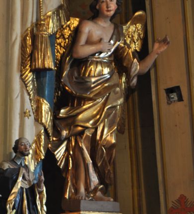 Zdjęcie nr 39: Ołtarz prostopadłościenny, murowany, w drewnianej obudowie, z drewnianą mensą. Antependium w kształcie leżącego prostokąta ujętego profilowaną ramą, dekorowane monogramem imienia MARIA w środku pola i symetrycznie rozłożonymi po bokach różanymi gałązkami. Na mensie ustawione architektoniczne tabernakulum. 
Nastawa w formie paludamentu podwiązanego po bokach sznurem z chwostami, lamowanego frędzlą, zwieńczonego baldachimem utworzonym z fragmentu wklęsło-wypukłego gzymsu z lambrekinem i rokokowym kartuszem. W polu paludamentu wnęka w kształcie stojącego prostokąta o wklęsłych górnych narożach w profilowanej ramie, ustawiona na cokole ujętym spływami wolutowymi. Wewnątrz obraz Matki Boskiej z Dzieciątkiem ujęty grubą ramą dekorowaną akantem i palmetami, ponad nim uskrzydlona główka anielska. Wnękę flankują dwa unoszące się putta, powyżej niej kartusz z monogramem Marii. Paludament dekorowany plastycznymi gwiazdami. Po bokach nastawy dwie bramki z otworami wejściowymi w formie stojącego prostokąta, zamkniętymi prostym gzymsem ze znajdującymi się powyżej postumentami dekorowanymi różami, na których stoją dwie figury aniołów. W górnej części, z obydwu stron nastawy poziome listwy konstrukcyjne mocujące całość retabulum do ścian bocznych prezbiterium, dekorowane są uskrzydlonymi główkami anielskimi z muszlami oraz roślinnymi festonami. Paludament polichromowany wewnątrz na biało, zewnątrz na niebiesko z pozłacanymi detalami.

