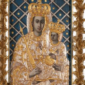 Zdjęcie nr 1: Obraz w kształcie pionowego prostokąta, z przedstawieniem Matki Boskiej z Dzieciątkiem, na niebieskim tle dekorowanym srebrzoną kratką, z malowanymi na drewnie partiami twarzy, dłoni i stóp oraz partiami szat i insygniami zasłoniętymi przez sukienki. Matka Boska ukazana w półpostaci, zwrócona delikatnie w trzech czwartych w lewą stronę, na lewym przedramieniu podtrzymuje Dzieciątko, a w prawej dłoni trzyma berło. Twarz pociągła, owalna, o dużych oczach, prostym, długim nosie i pełnych ustach, z odsłoniętym dużym prawym uchem. Łagodne rysy wydobyte zostały ostrym kontrastem światłocienia. Na głowie ma koronę zamkniętą, wokół głowy glorię promienistą i nimb zamknięty. Ubrana jest w suknię, dekorowaną gałązkami kwiatowymi, przepasaną w talii wstążką oraz płaszcz narzucony na ramiona, z ośmioramienną gwiazdą na prawym ramieniu, dekorowany ornamentem rocaille&#039;owym z ośmioramienną gwiazdą na prawym ramieniu. Dzieciątko w pozycji siedzącej, zwrócone jest w trzech czwartych w prawą stronę, prawą dłonią błogosławi, lewą przytrzymuje na kolanie jabłko królewskie. Jego twarz jest okrągła o rysach wydobytych silnym światłocieniem, o dużych oczach, niewielkim nosie i pełnych ustach z odsłoniętym lewym, dużym uchem. Na głowie ma koronę zamkniętą, wokół twarzy glorię promienistą oraz nimb zamknięty. Ubrane jest w tunikę dekorowaną gałązkami kwiatowymi i lamówką. Obraz ujęty posrebrzaną ramą z plastycznym, rokokowym i pozłacanym ornamentem. 