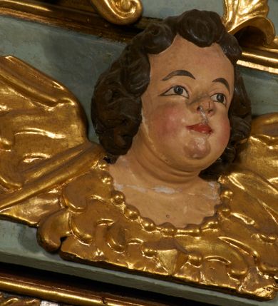 Zdjęcie nr 6: Obraz w kształcie pionowego prostokąta, z przedstawieniem Matki Boskiej z Dzieciątkiem, na niebieskim tle dekorowanym srebrzoną kratką, z malowanymi na drewnie partiami twarzy, dłoni i stóp oraz partiami szat i insygniami zasłoniętymi przez sukienki. Matka Boska ukazana w półpostaci, zwrócona delikatnie w trzech czwartych w lewą stronę, na lewym przedramieniu podtrzymuje Dzieciątko, a w prawej dłoni trzyma berło. Twarz pociągła, owalna, o dużych oczach, prostym, długim nosie i pełnych ustach, z odsłoniętym dużym prawym uchem. Łagodne rysy wydobyte zostały ostrym kontrastem światłocienia. Na głowie ma koronę zamkniętą, wokół głowy glorię promienistą i nimb zamknięty. Ubrana jest w suknię, dekorowaną gałązkami kwiatowymi, przepasaną w talii wstążką oraz płaszcz narzucony na ramiona, z ośmioramienną gwiazdą na prawym ramieniu, dekorowany ornamentem rocaille'owym z ośmioramienną gwiazdą na prawym ramieniu. Dzieciątko w pozycji siedzącej, zwrócone jest w trzech czwartych w prawą stronę, prawą dłonią błogosławi, lewą przytrzymuje na kolanie jabłko królewskie. Jego twarz jest okrągła o rysach wydobytych silnym światłocieniem, o dużych oczach, niewielkim nosie i pełnych ustach z odsłoniętym lewym, dużym uchem. Na głowie ma koronę zamkniętą, wokół twarzy glorię promienistą oraz nimb zamknięty. Ubrane jest w tunikę dekorowaną gałązkami kwiatowymi i lamówką. Obraz ujęty posrebrzaną ramą z plastycznym, rokokowym i pozłacanym ornamentem. 