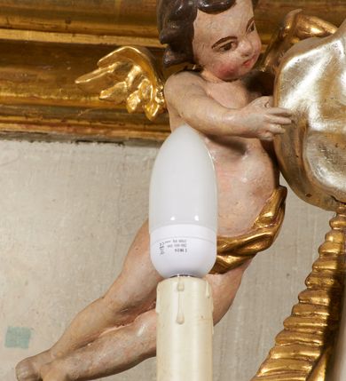 Zdjęcie nr 23: Tabernakulum architektoniczne, jednokondygnacyjne, pięcioosiowe. Osie wydzielone są sześcioma kanelowanymi kolumienkami na wysokich, profilowanych cokołach, z liściastymi kapitelami, podtrzymującymi profilowane belkowanie wyłamane na ich osiach. W polach pomiędzy kolumnami znajdują się nisze ujęte profilowaną ramą z uszakami. W czterech bocznych niszach, na trójdzielnych, profilowanych wspornikach stoją płaskorzeźbione postacie czterech ewangelistów na tle muszli palmetowych. Figurki są całopostaciowe, w ujęciu frontalnym, w złotych szatach, podtrzymują otwarte księgi, wskazując na tekst. Drzwiczki znajdują się na osi środkowej, zamknięte są półkoliście, płaskorzeźbione z przedstawieniem kielicha z koroną cierniową i z hostią w glorii promienistej. Kielich flankowany jest kłosami zbóż i winną latoroślą oraz winogronami. W partii belkowania płaskorzeźbiona dekoracja złożona z naprzemiennie ułożonych główek anielskich o złotych skrzydłach i płaskich rozetek. Tron wystawienia w formie baldachimu, z lambrekinem i chwostami, zwieńczony jest kulą z krzyżem, z podwieszonym z tyłu paludamentem podtrzymywanym przez parę puttów. Struktura polichromowana na biało, profile i detale pozłocone. 