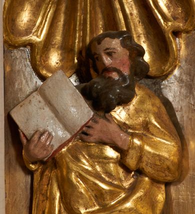 Zdjęcie nr 19: Tabernakulum architektoniczne, jednokondygnacyjne, pięcioosiowe. Osie wydzielone są sześcioma kanelowanymi kolumienkami na wysokich, profilowanych cokołach, z liściastymi kapitelami, podtrzymującymi profilowane belkowanie wyłamane na ich osiach. W polach pomiędzy kolumnami znajdują się nisze ujęte profilowaną ramą z uszakami. W czterech bocznych niszach, na trójdzielnych, profilowanych wspornikach stoją płaskorzeźbione postacie czterech ewangelistów na tle muszli palmetowych. Figurki są całopostaciowe, w ujęciu frontalnym, w złotych szatach, podtrzymują otwarte księgi, wskazując na tekst. Drzwiczki znajdują się na osi środkowej, zamknięte są półkoliście, płaskorzeźbione z przedstawieniem kielicha z koroną cierniową i z hostią w glorii promienistej. Kielich flankowany jest kłosami zbóż i winną latoroślą oraz winogronami. W partii belkowania płaskorzeźbiona dekoracja złożona z naprzemiennie ułożonych główek anielskich o złotych skrzydłach i płaskich rozetek. Tron wystawienia w formie baldachimu, z lambrekinem i chwostami, zwieńczony jest kulą z krzyżem, z podwieszonym z tyłu paludamentem podtrzymywanym przez parę puttów. Struktura polichromowana na biało, profile i detale pozłocone. 