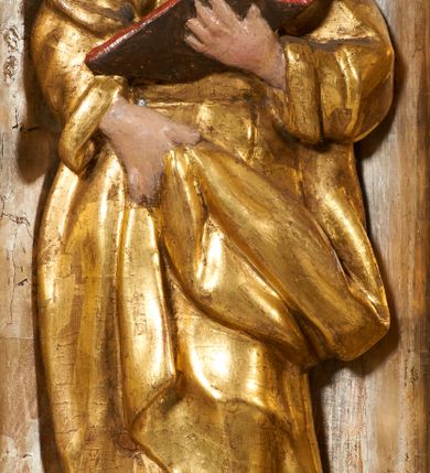 Zdjęcie nr 14: Tabernakulum architektoniczne, jednokondygnacyjne, pięcioosiowe. Osie wydzielone są sześcioma kanelowanymi kolumienkami na wysokich, profilowanych cokołach, z liściastymi kapitelami, podtrzymującymi profilowane belkowanie wyłamane na ich osiach. W polach pomiędzy kolumnami znajdują się nisze ujęte profilowaną ramą z uszakami. W czterech bocznych niszach, na trójdzielnych, profilowanych wspornikach stoją płaskorzeźbione postacie czterech ewangelistów na tle muszli palmetowych. Figurki są całopostaciowe, w ujęciu frontalnym, w złotych szatach, podtrzymują otwarte księgi, wskazując na tekst. Drzwiczki znajdują się na osi środkowej, zamknięte są półkoliście, płaskorzeźbione z przedstawieniem kielicha z koroną cierniową i z hostią w glorii promienistej. Kielich flankowany jest kłosami zbóż i winną latoroślą oraz winogronami. W partii belkowania płaskorzeźbiona dekoracja złożona z naprzemiennie ułożonych główek anielskich o złotych skrzydłach i płaskich rozetek. Tron wystawienia w formie baldachimu, z lambrekinem i chwostami, zwieńczony jest kulą z krzyżem, z podwieszonym z tyłu paludamentem podtrzymywanym przez parę puttów. Struktura polichromowana na biało, profile i detale pozłocone. 