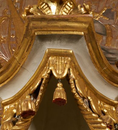 Zdjęcie nr 9: Tabernakulum architektoniczne, jednokondygnacyjne, pięcioosiowe. Osie wydzielone są sześcioma kanelowanymi kolumienkami na wysokich, profilowanych cokołach, z liściastymi kapitelami, podtrzymującymi profilowane belkowanie wyłamane na ich osiach. W polach pomiędzy kolumnami znajdują się nisze ujęte profilowaną ramą z uszakami. W czterech bocznych niszach, na trójdzielnych, profilowanych wspornikach stoją płaskorzeźbione postacie czterech ewangelistów na tle muszli palmetowych. Figurki są całopostaciowe, w ujęciu frontalnym, w złotych szatach, podtrzymują otwarte księgi, wskazując na tekst. Drzwiczki znajdują się na osi środkowej, zamknięte są półkoliście, płaskorzeźbione z przedstawieniem kielicha z koroną cierniową i z hostią w glorii promienistej. Kielich flankowany jest kłosami zbóż i winną latoroślą oraz winogronami. W partii belkowania płaskorzeźbiona dekoracja złożona z naprzemiennie ułożonych główek anielskich o złotych skrzydłach i płaskich rozetek. Tron wystawienia w formie baldachimu, z lambrekinem i chwostami, zwieńczony jest kulą z krzyżem, z podwieszonym z tyłu paludamentem podtrzymywanym przez parę puttów. Struktura polichromowana na biało, profile i detale pozłocone. 