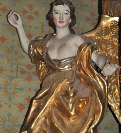 Zdjęcie nr 7: Obie rzeźby są ścięte z tyłu i głęboko drążone. Figury zwrócone są frontalnie z głowami skierowanymi w stronę ołtarza, stoją w kontrapoście. Anioł na lewej bramce unosi prawą rękę w górę, lewą opuszcza w dół. Anioł z prawej bramki prawą rękę kładzie na piersi, lewa zaś jest ugięta i i uniesiona. Anioły mają pociągłe twarze o uwypuklonych brodach, prostych, dużych nosach i szerokich nozdrzach, oczach o łukowatych górnych powiekach i półkolistych łukach brwiowych, pełnych ustach z wydrążonymi kącikami. Włosy opadające na plecy rzeźbione są w grube, falowane i zmierzwione pukle. Postacie ubrane są w tuniki przepasane w talii, przykrywające jedno ramię szerokim rękawem, odsłaniające część torsu i drugą rękę oraz w płaszcze zawinięte w partii ud. Polichromia w partiach ciała naturalistyczna, szaty pozłacane.  
